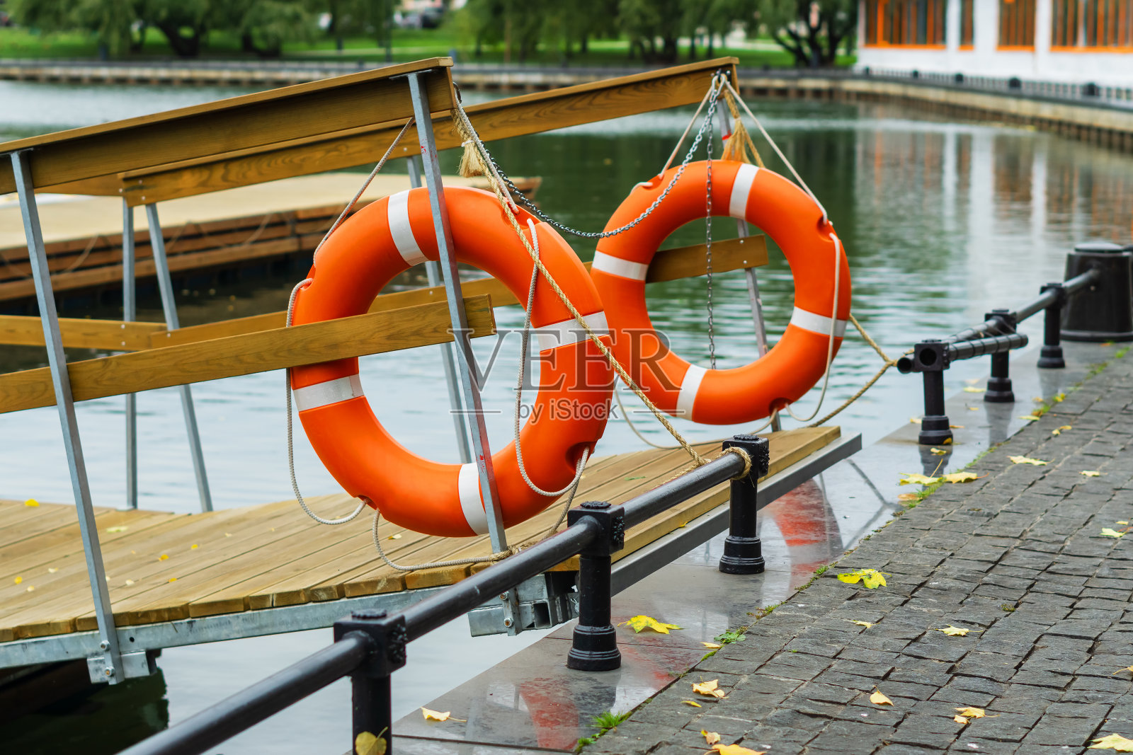 木码头的入口处悬挂着两个橙色的塑料救生圈。照片摄影图片
