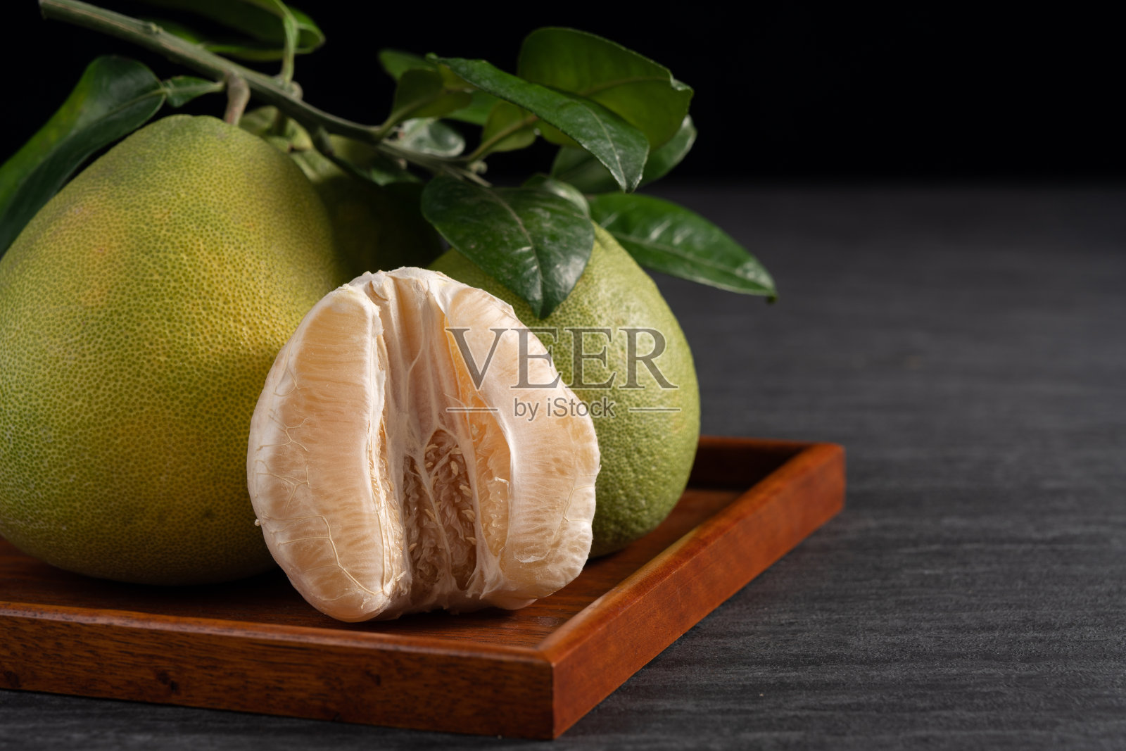 新鲜的柚子水果在黑色石板的背景。照片摄影图片