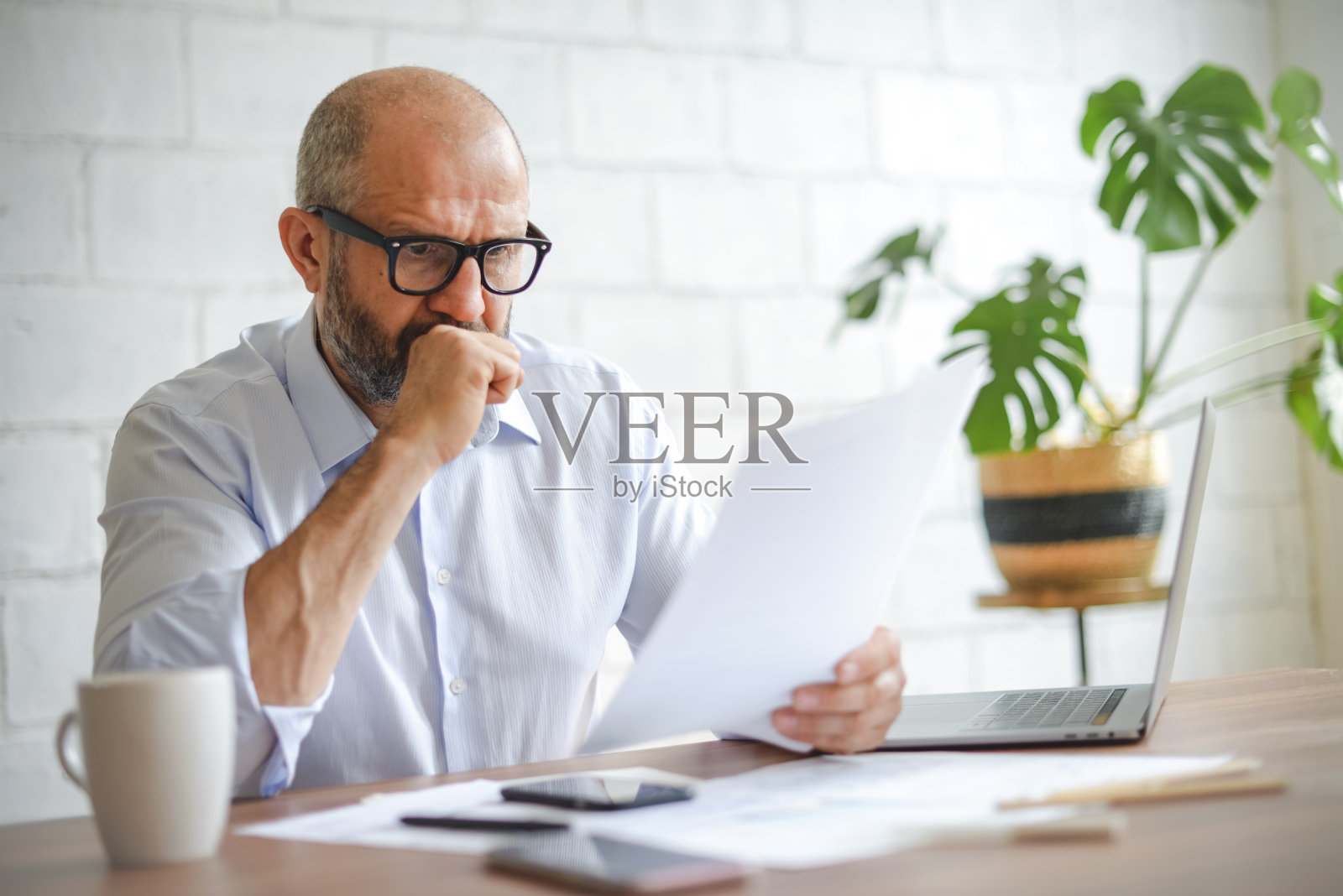 在办公室工作的成熟成年人(带着笔记本电脑、文书工作、消极情绪)照片摄影图片