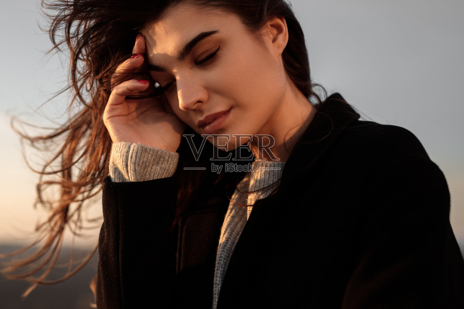 悲伤的女人穿着黑色外套摸着头照片摄影图片