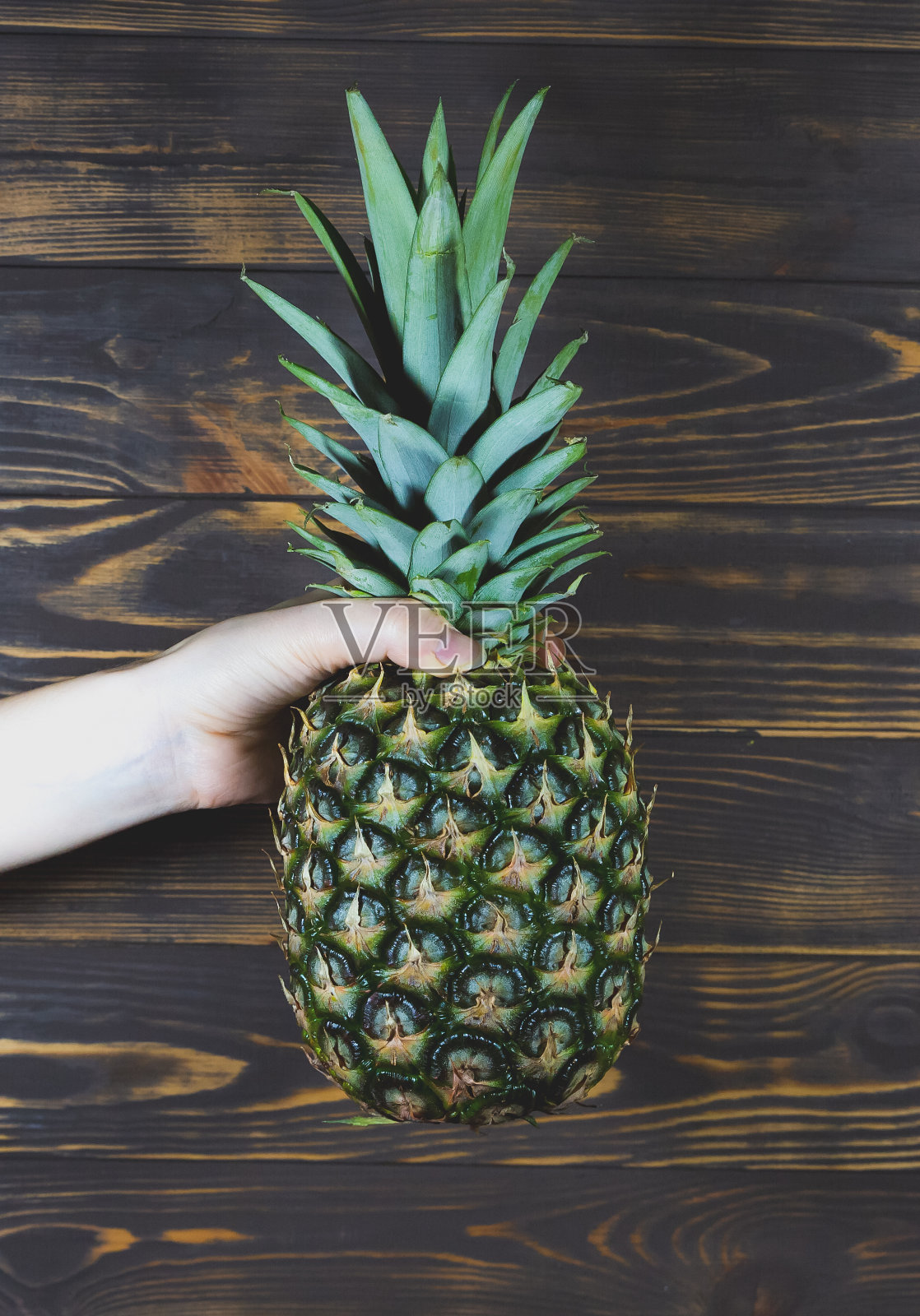 女人拿着菠萝。木制背景。照片摄影图片
