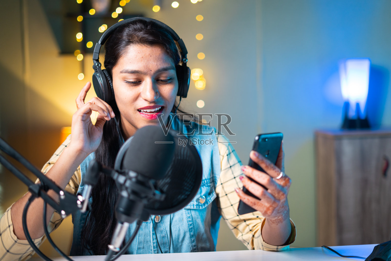 年轻的印度女孩视频博主直播或流媒体,并检查点赞,评论或在社交媒体上与频道订户聊天照片摄影图片