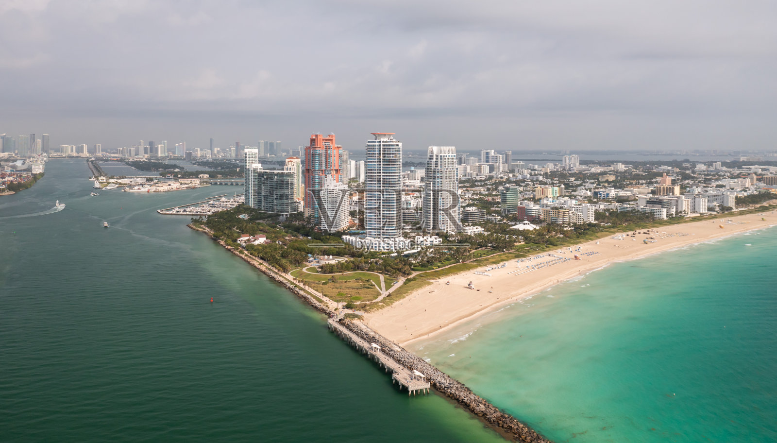 令人难以置信的白天鸟瞰图的南角高层公寓俯瞰迈阿密海滩与沙滩衬着碧绿的大西洋水域与多云的天空。照片摄影图片