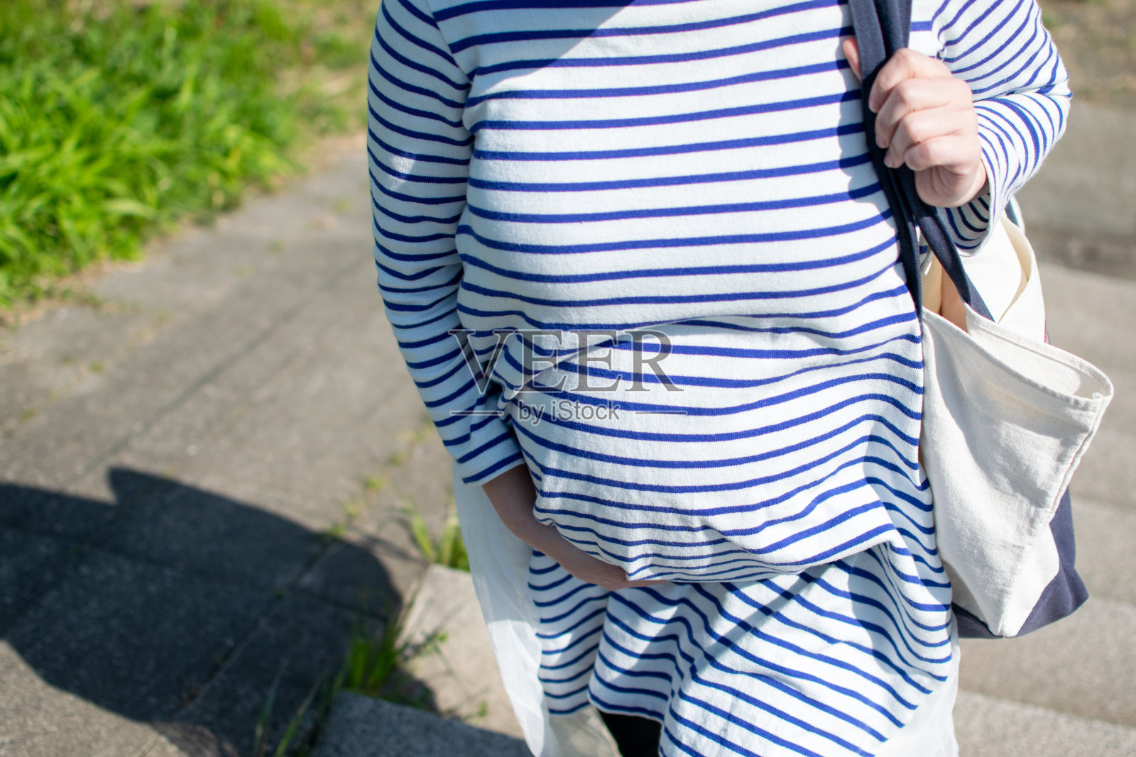 一个年轻的亚洲孕妇带着野餐的大手提袋爬楼梯照片摄影图片