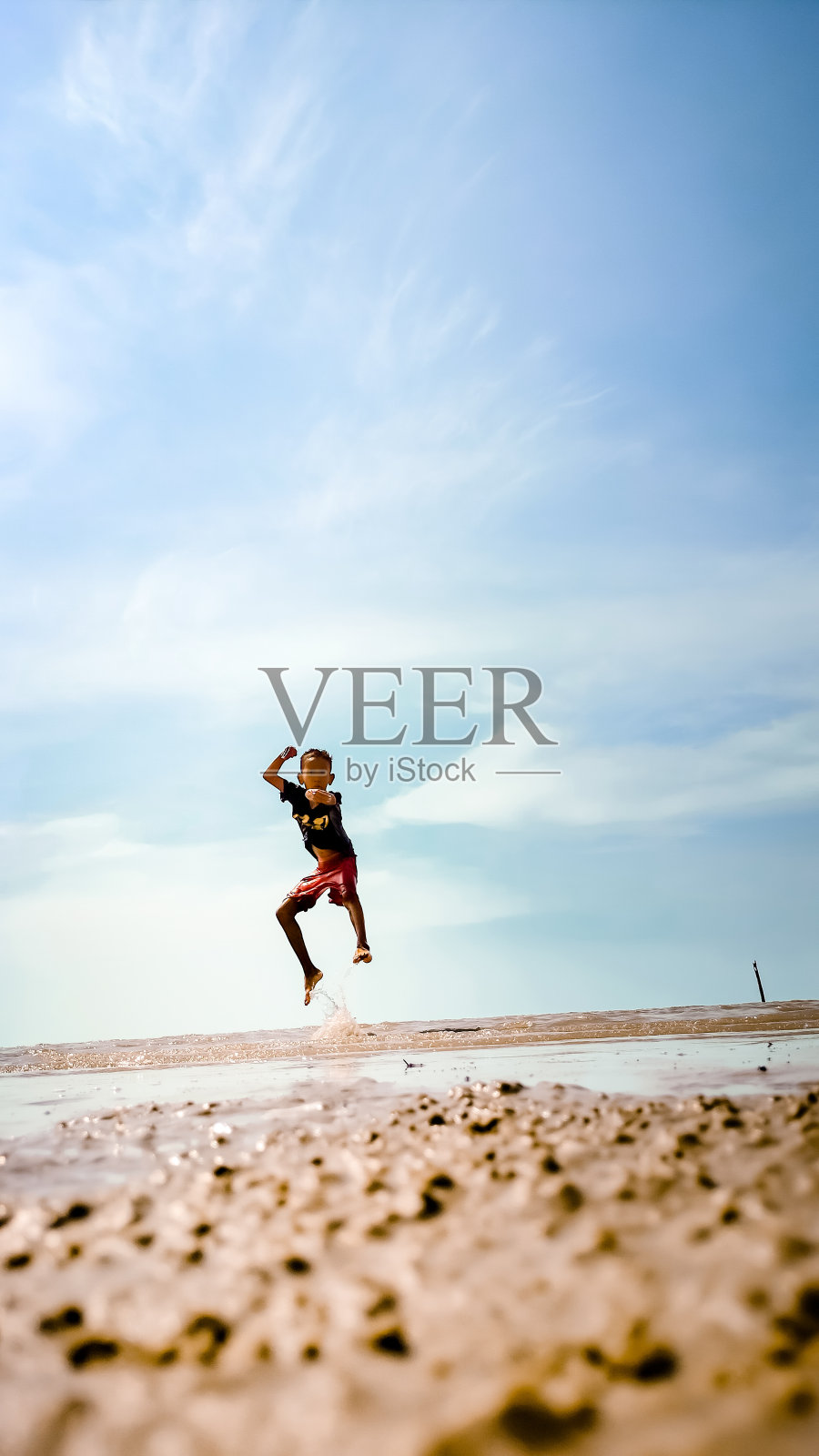 一个男孩在海滩上跳跃照片摄影图片