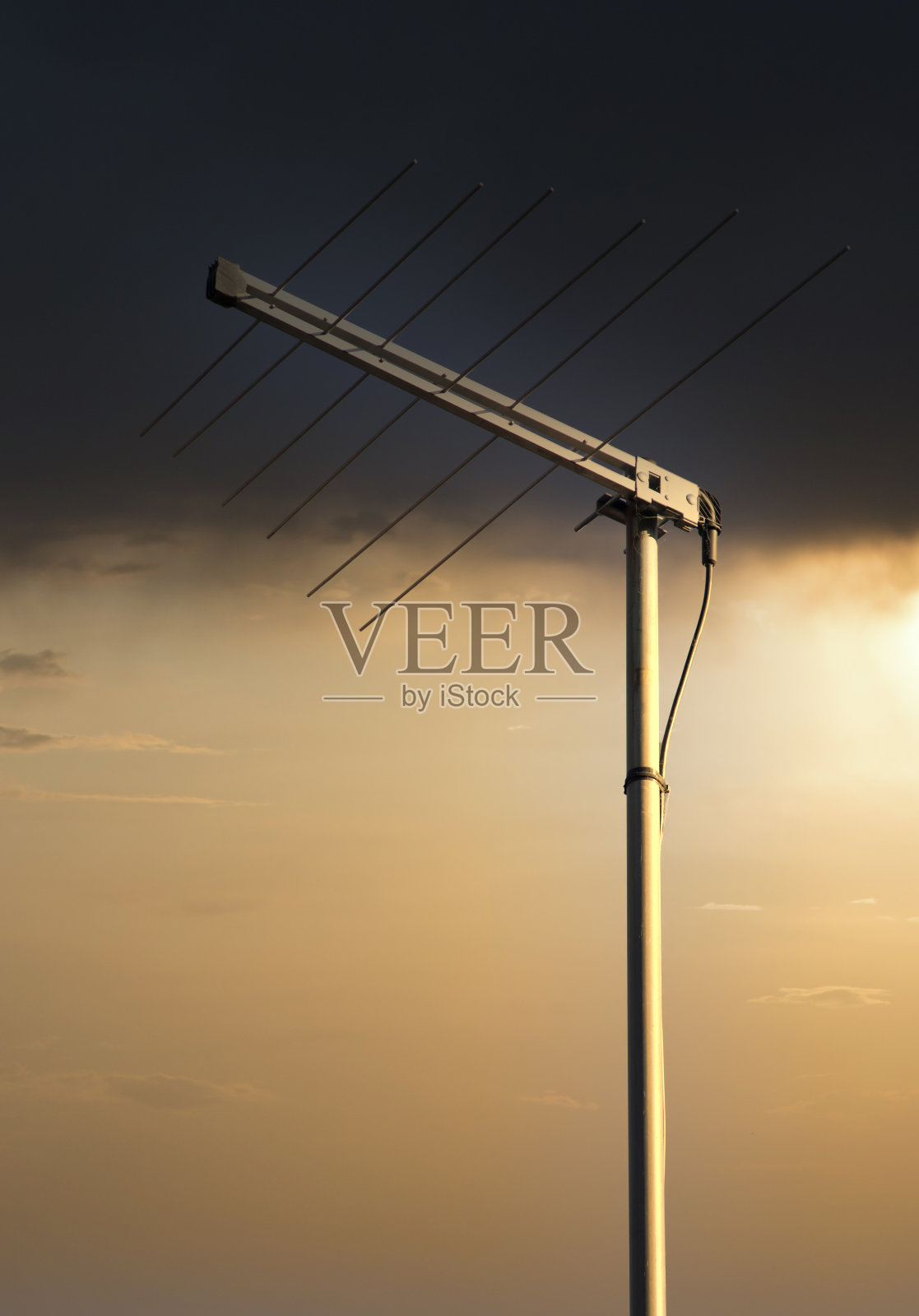 房屋屋顶上的金属电视天线,背景是橙色的日落天空照片摄影图片