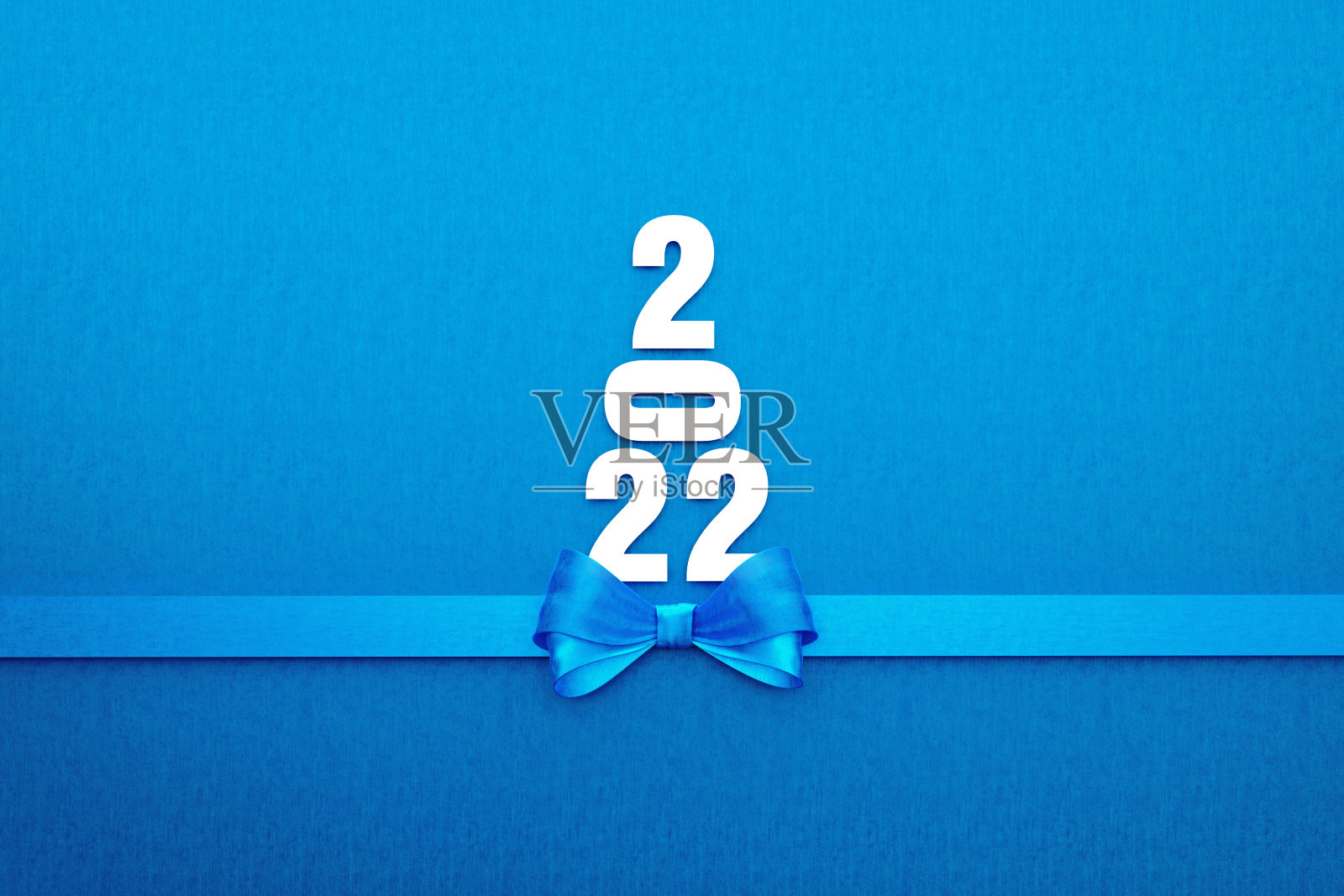 2022文本形成了蓝色背景上的蓝色蝴蝶结圣诞树照片摄影图片