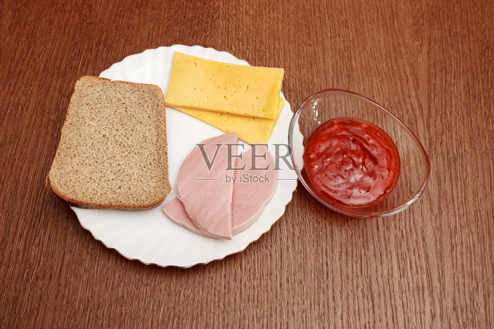 奶酪片、面包片和香肠片放在盘子和碟子上,再配上辣椒酱照片摄影图片