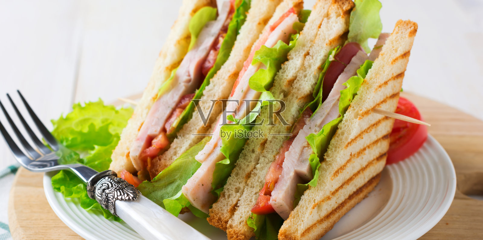 早餐三明治,填充番茄,火腿和生菜,木制背景。有选择性的重点。照片摄影图片