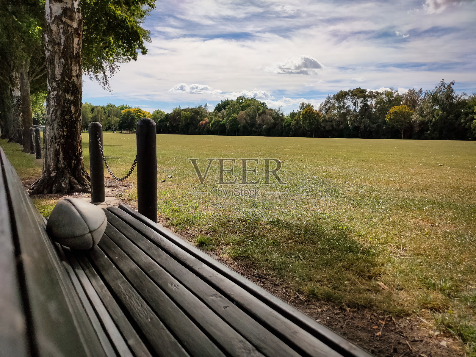 一个人在公园长椅上玩橄榄球。体育的概念照片摄影图片