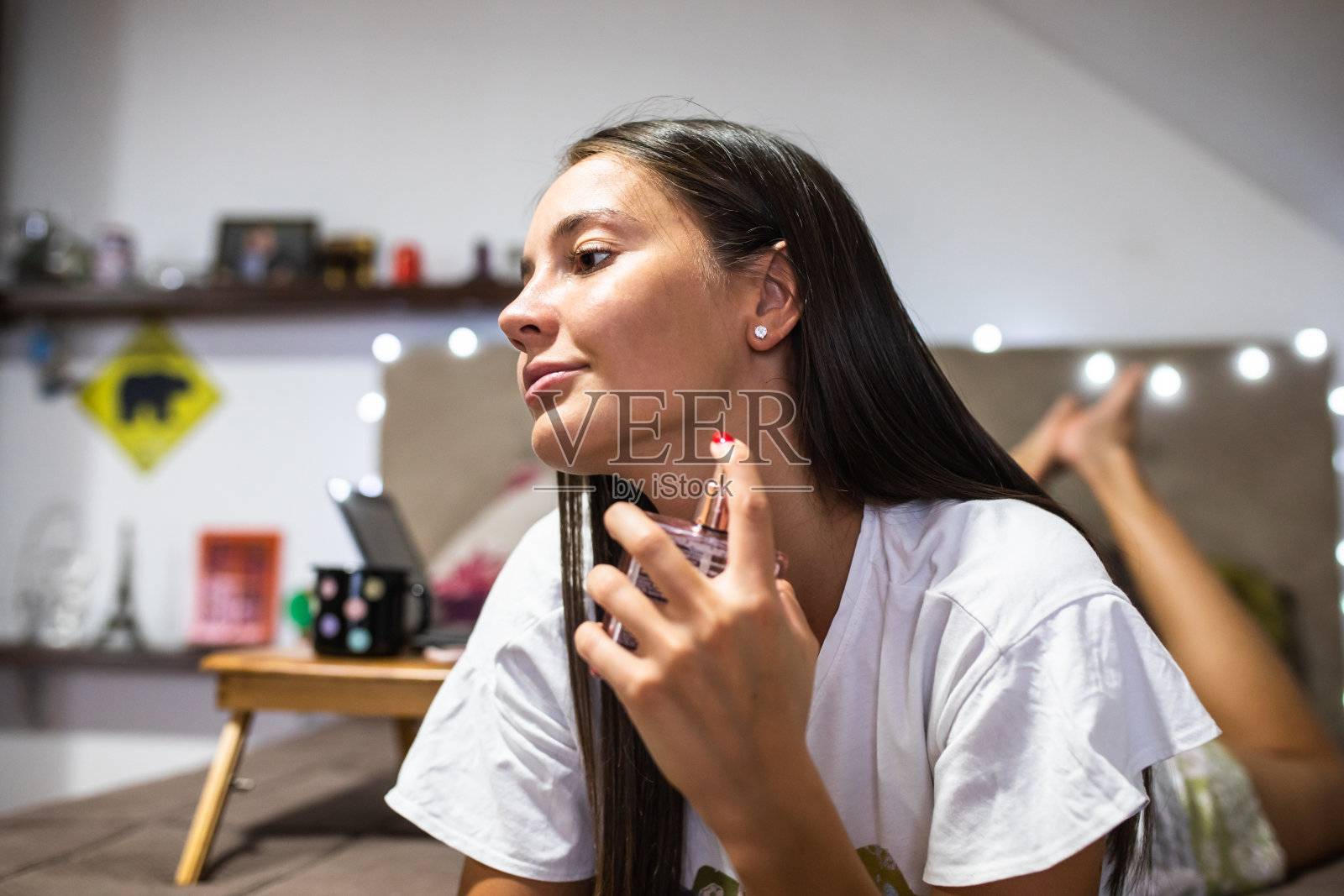 一个年轻漂亮的女人在床上喷香水照片摄影图片