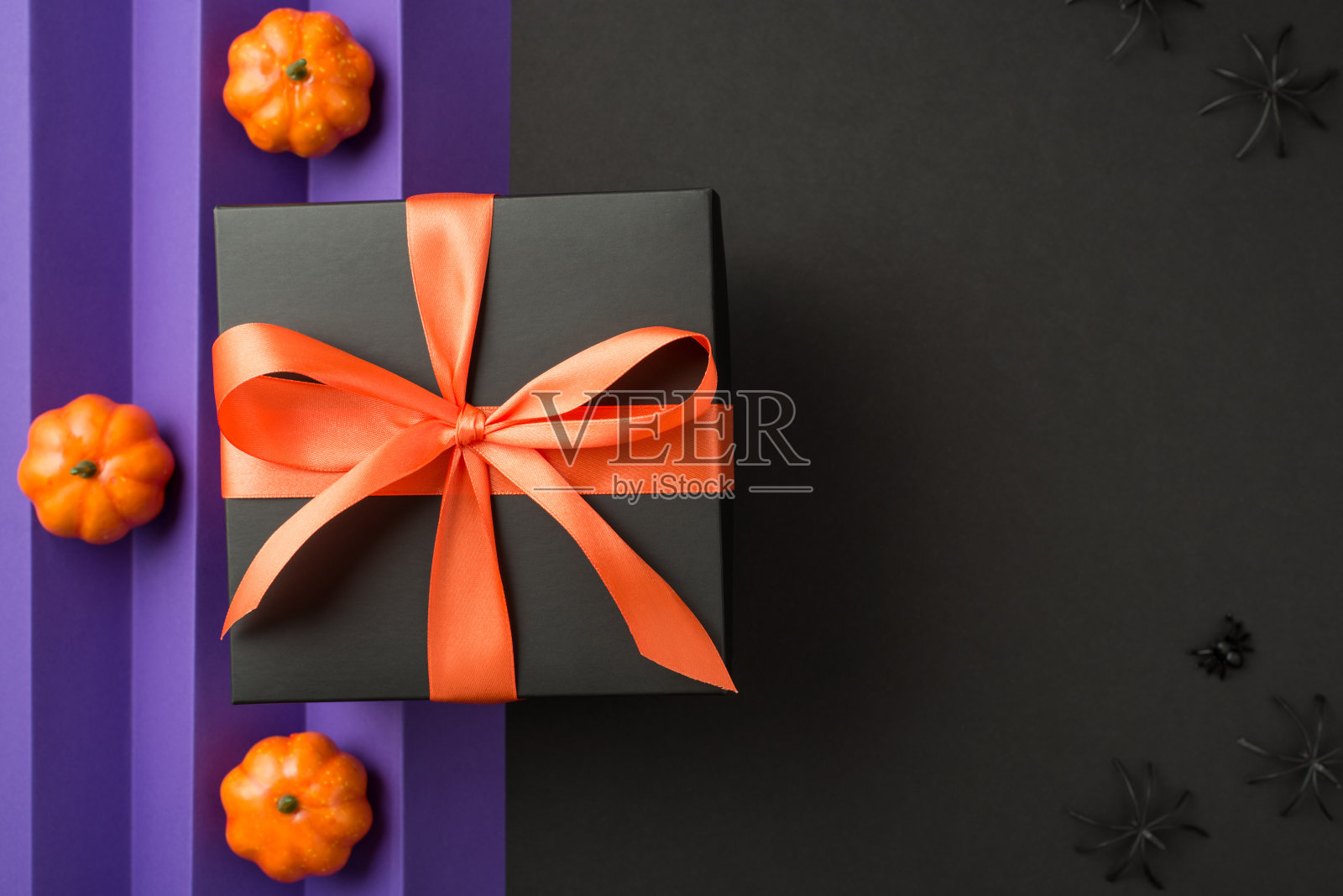 俯视图照片的万圣节组成黑色礼盒与橙色丝带蝴蝶结小南瓜和蜘蛛孤立的背面和紫色页垂直折叠背景与空的空间照片摄影图片