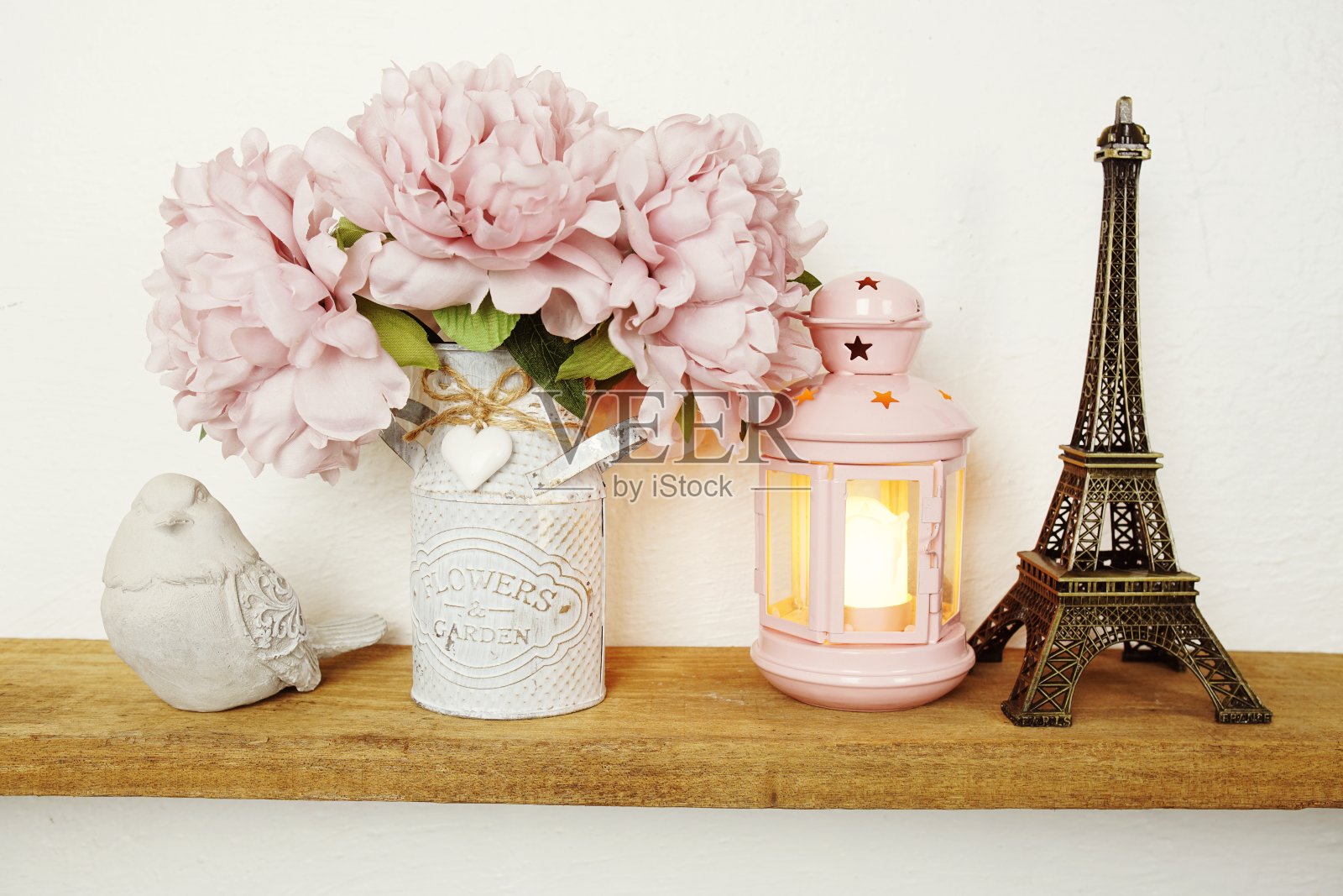 木制的架子上装饰着埃菲尔铁塔纪念品、烛光、花束和小鸟雕像照片摄影图片