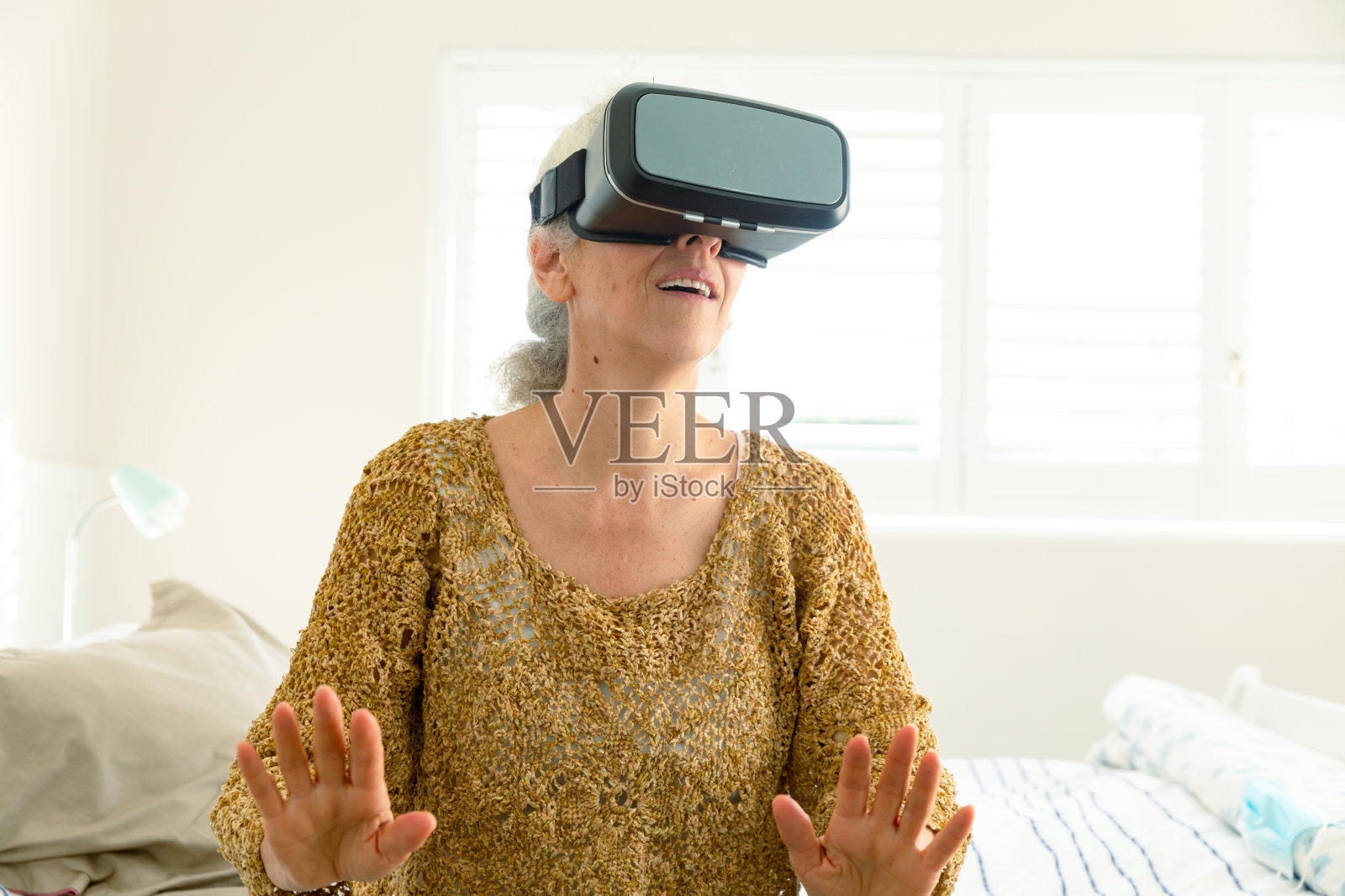 快乐的白人老年妇女戴着虚拟现实头盔,玩得很开心照片摄影图片