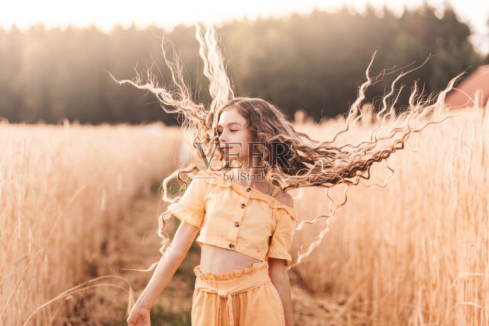 阳光明媚的日子里走在麦田里的长发漂亮少女照片摄影图片