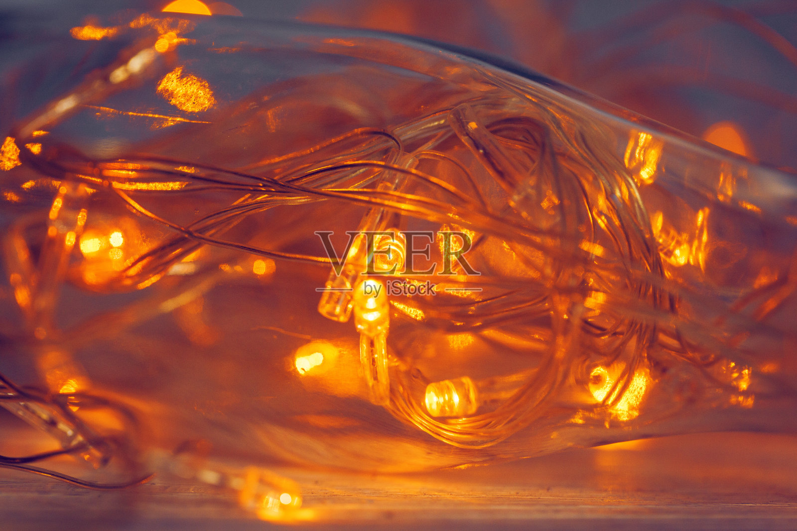 在黑暗的背景下,灯光在玻璃瓶中形成花环照片摄影图片