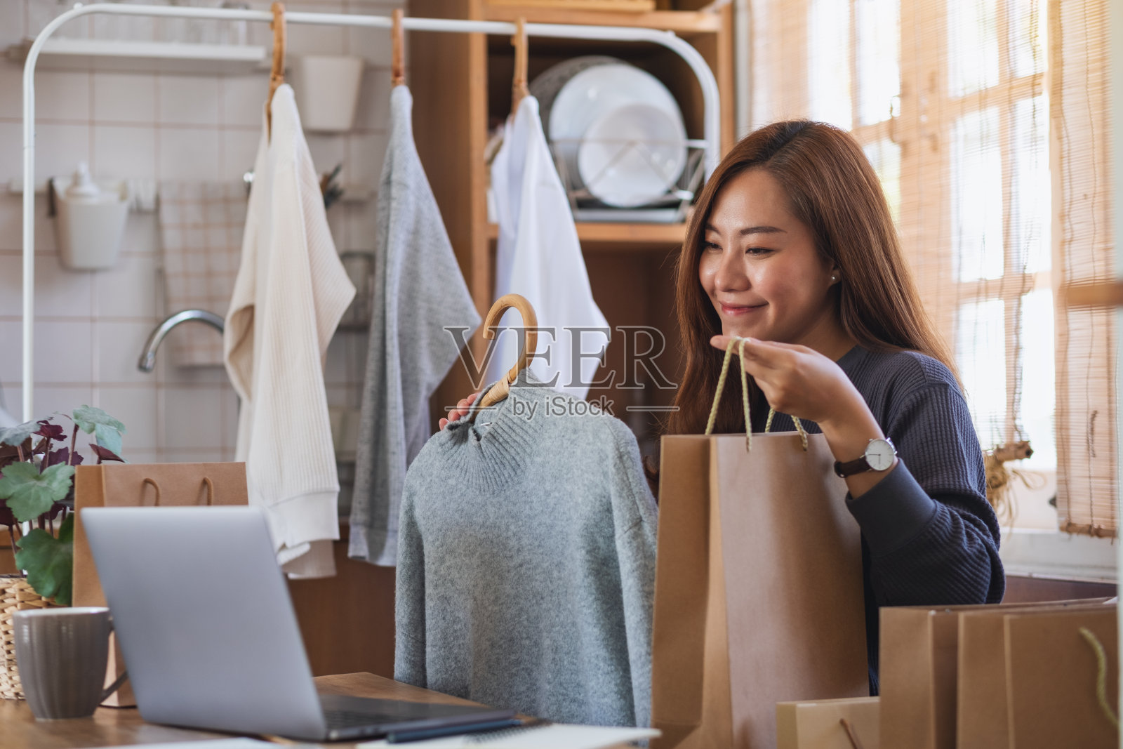 用笔记本电脑在网上卖衣服或在家在社交媒体上评论产品的企业家照片摄影图片