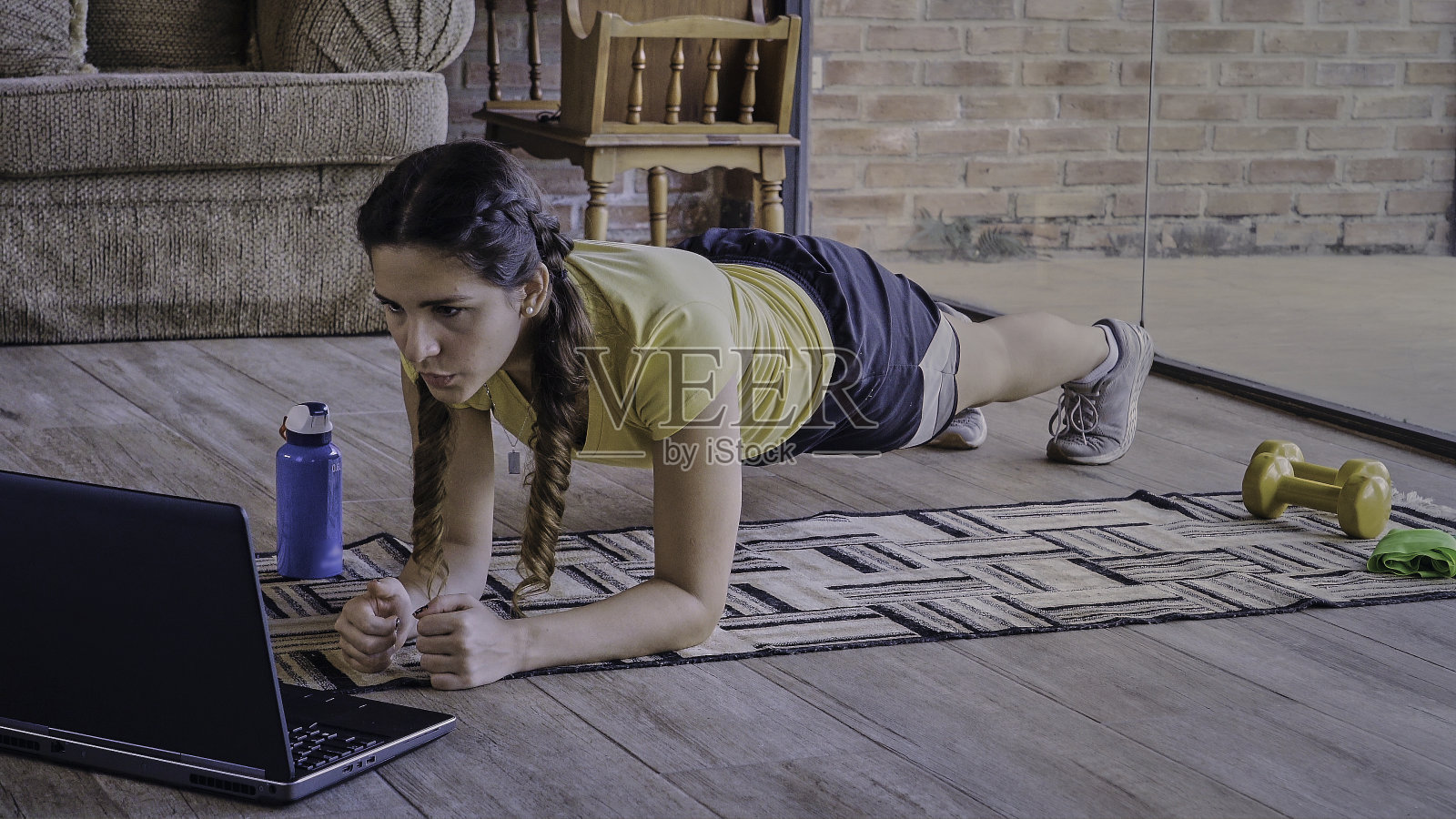 西班牙裔年轻女子一边在家锻炼一边看在线教程。照片摄影图片