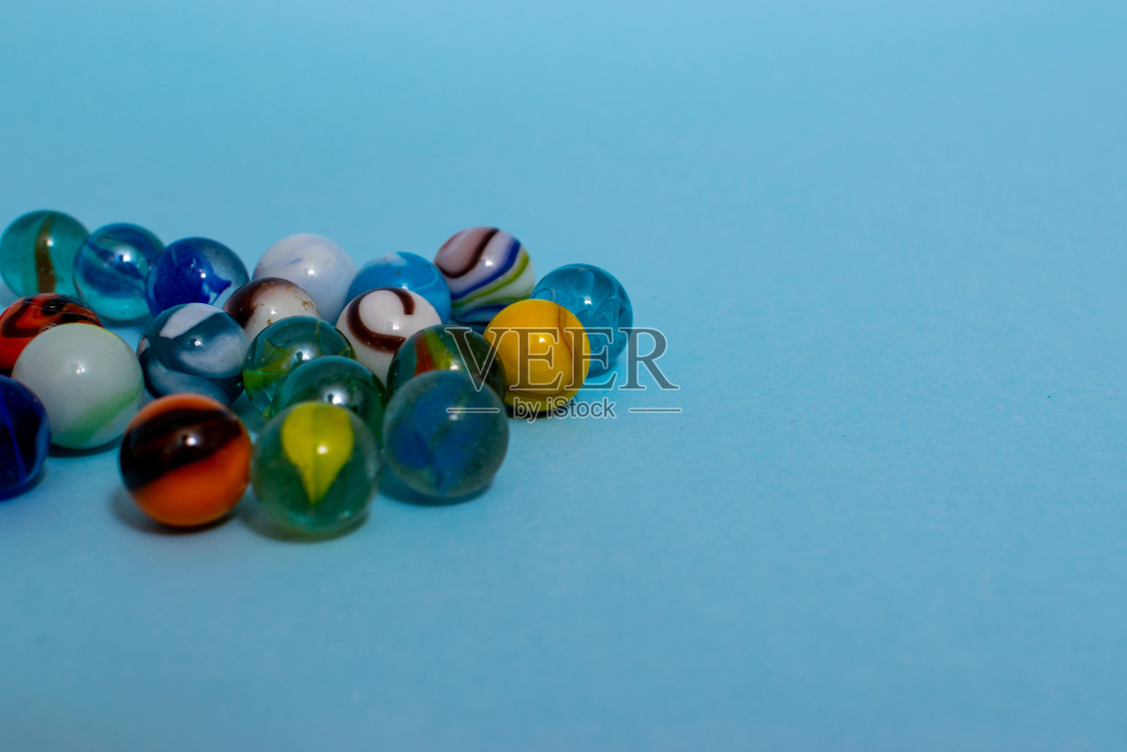 彩色玻璃弹珠孤立在蓝色背景上,靠近玩具。照片摄影图片
