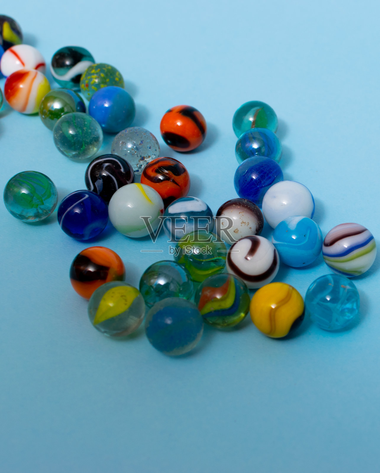 彩色玻璃弹珠孤立在蓝色背景上,靠近玩具。照片摄影图片
