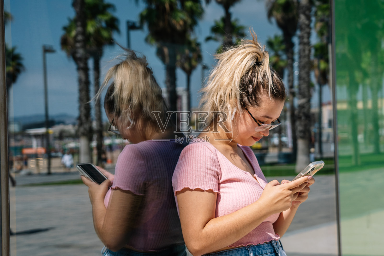 年轻的金发女人看着街上的手机照片摄影图片
