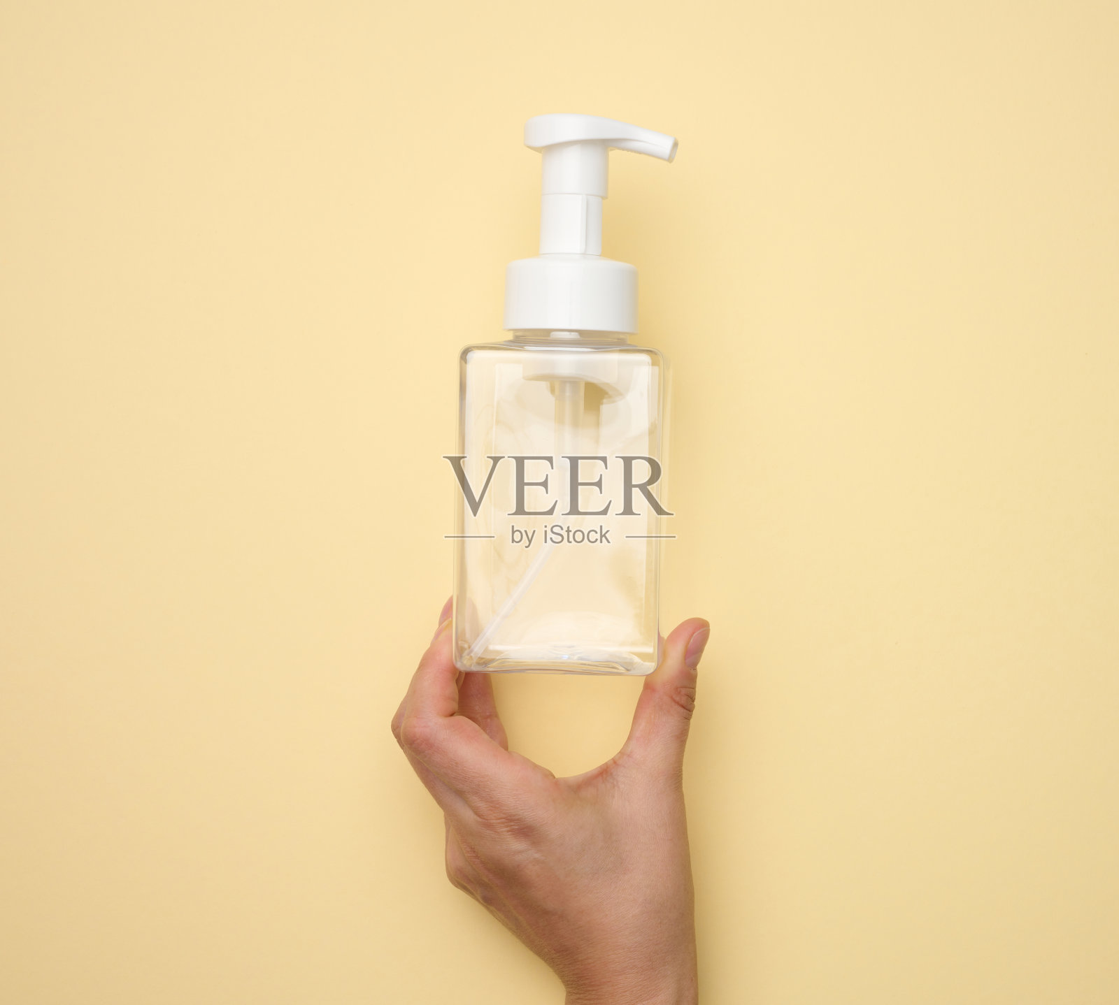 女性手握空塑料容器与分配器液体产品,肥皂或洗发水在米色背景照片摄影图片