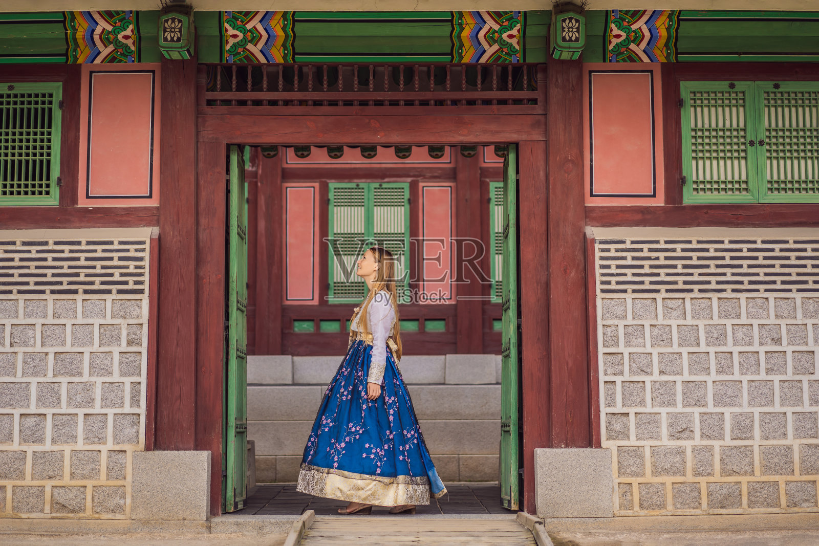 身穿韩服的年轻白种女游客在韩国宫殿。韩国旅游概念。国家韩国的服装。为游客提供的娱乐——试穿韩国民族服装照片摄影图片