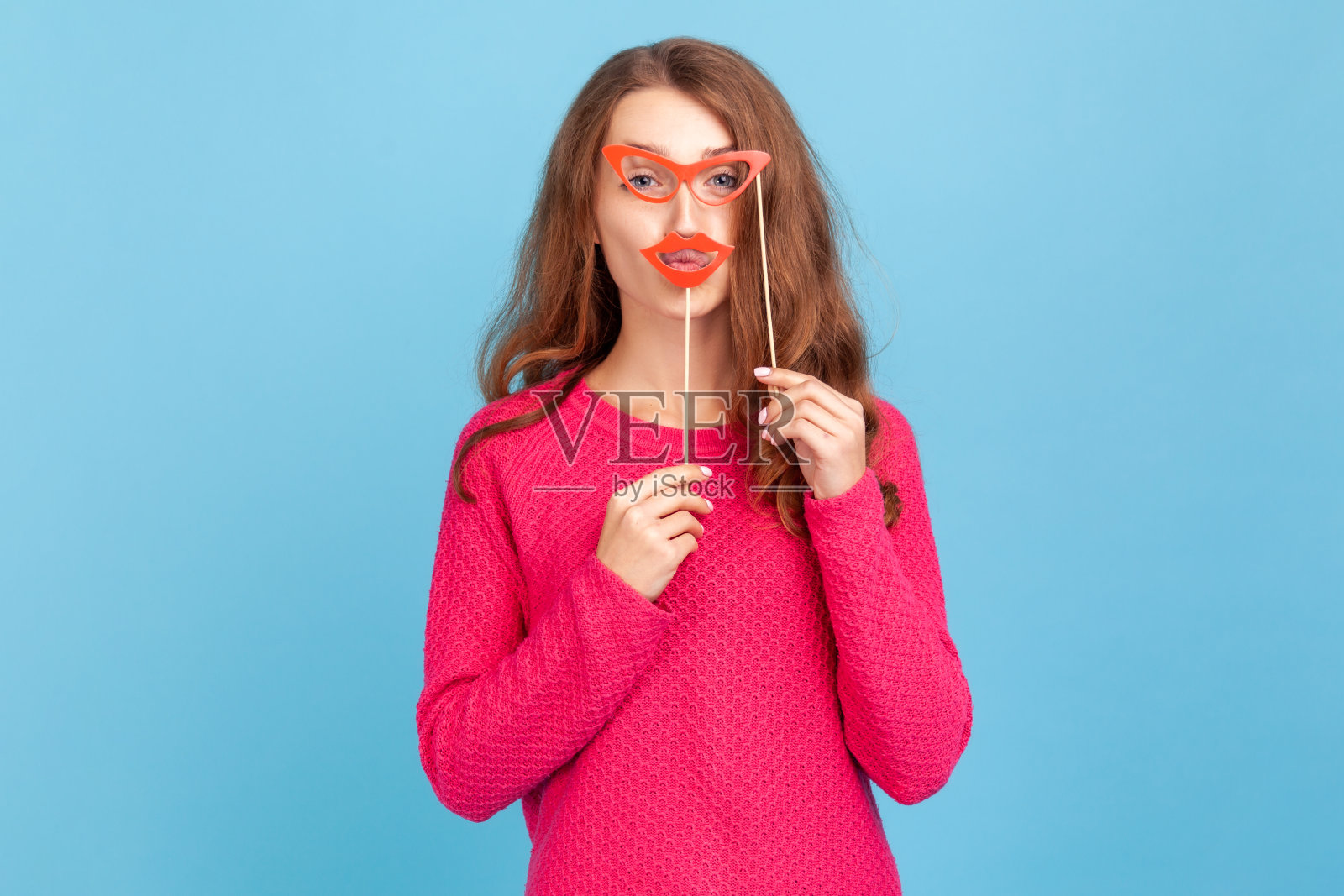 女人拿着纸眼镜和嘴唇,看着相机,有节日的气氛,戴着派对道具。照片摄影图片