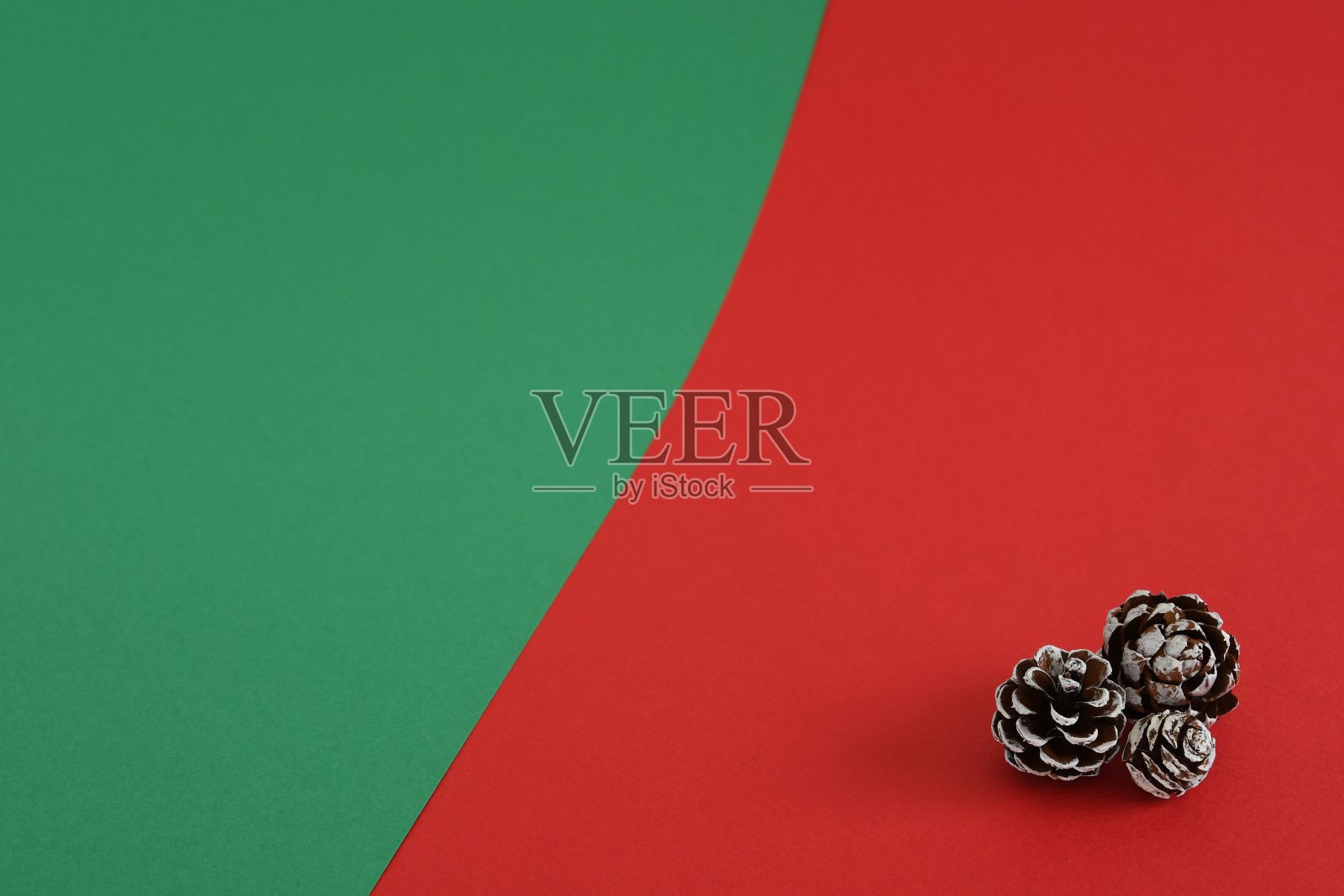 红色和绿色背景上的圣诞松果。照片摄影图片