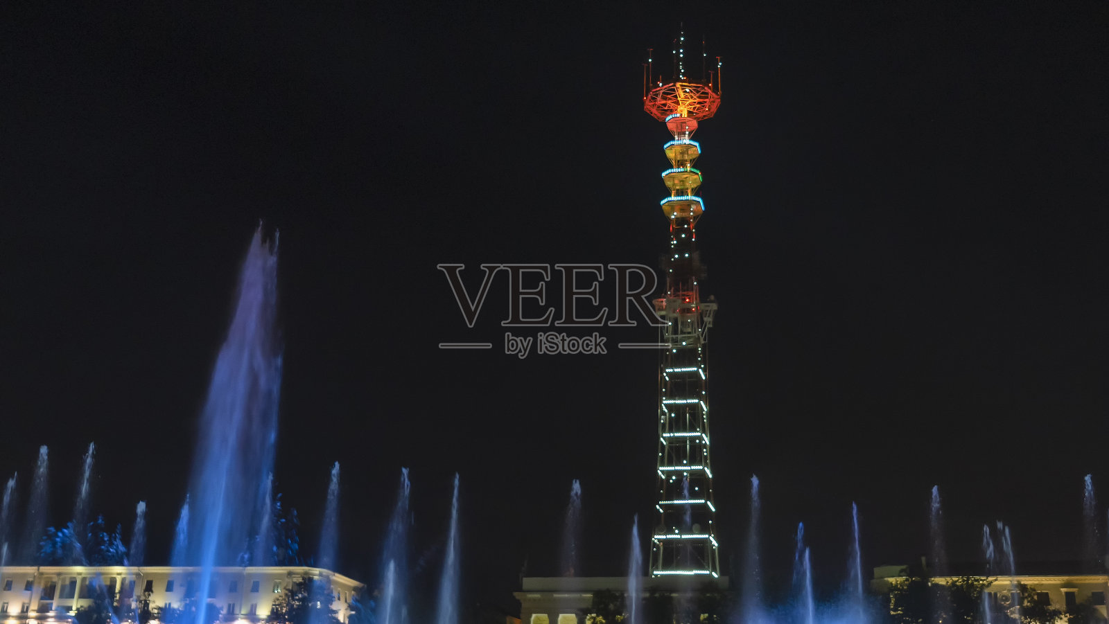 电视塔在节日的灯光下。在前景喷泉与长曝光水滴。节日的概念。照片摄影图片