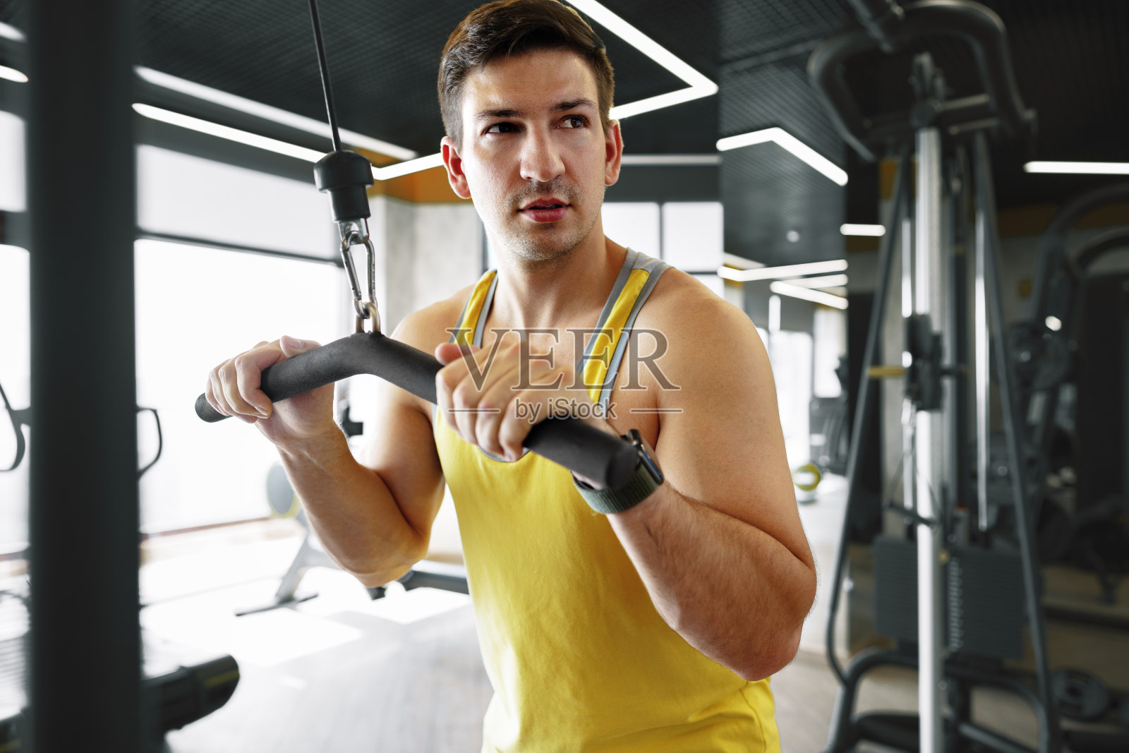 年轻的健美运动员在健身房做二头肌的重量锻炼照片摄影图片