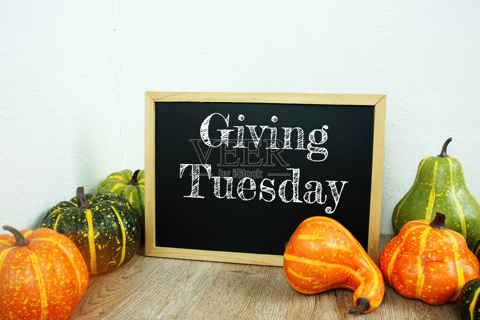 给星期二印刷文本在板画架模拟与人造花和南瓜木制桌子室内装饰照片摄影图片