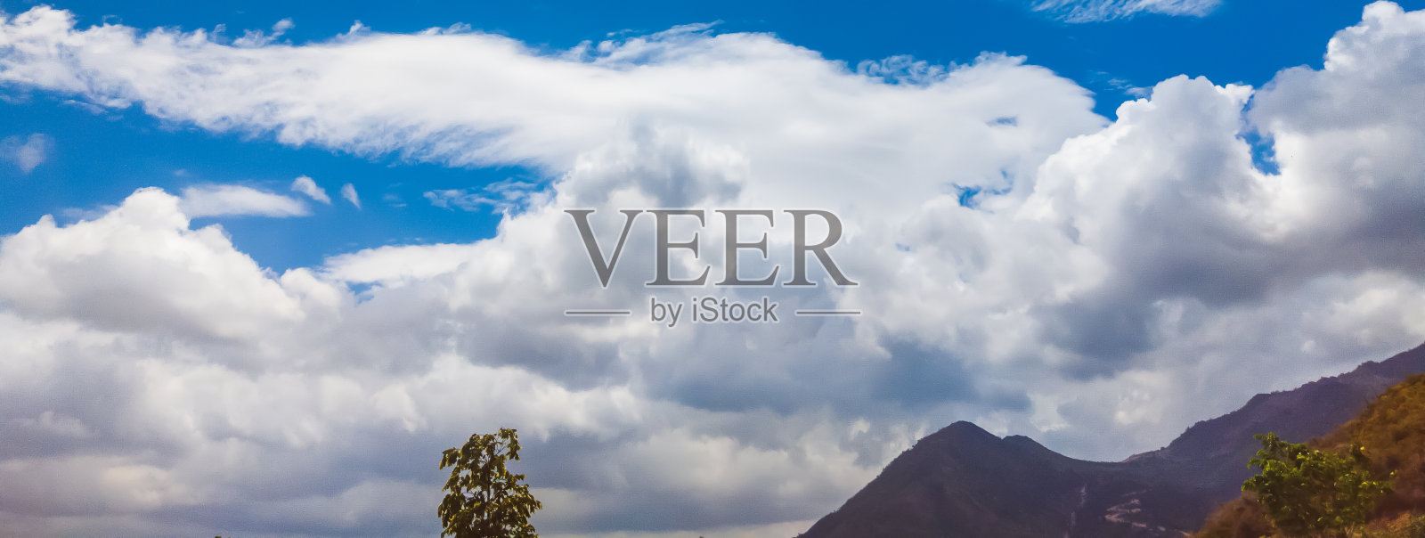 蔚蓝的天空和白天的许多白云。自然的天空,山脉和许多绿色的树木和草组成。非常适合用于设计或墙纸照片摄影图片