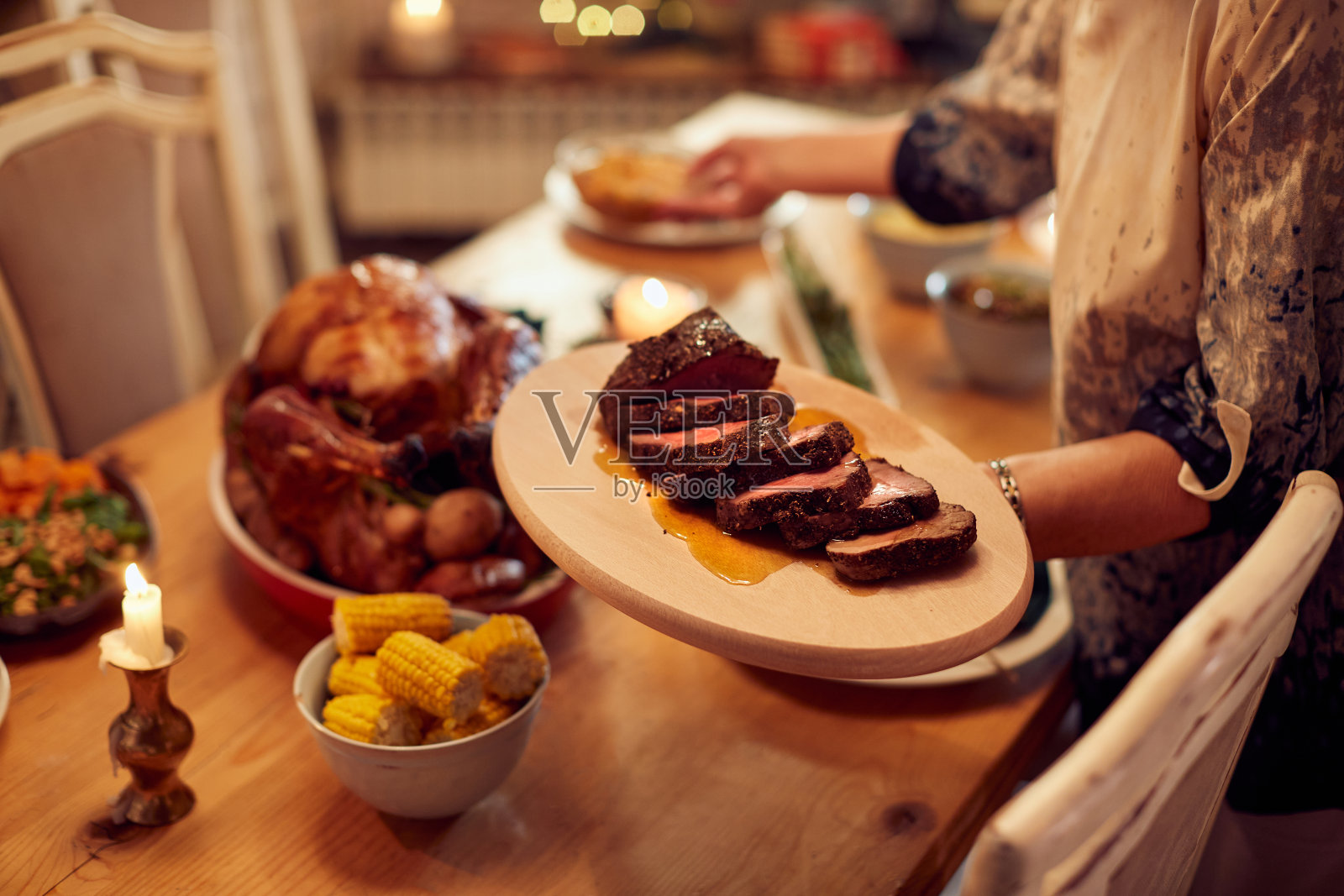一个女人在圣诞节的餐桌上菜的特写镜头。照片摄影图片