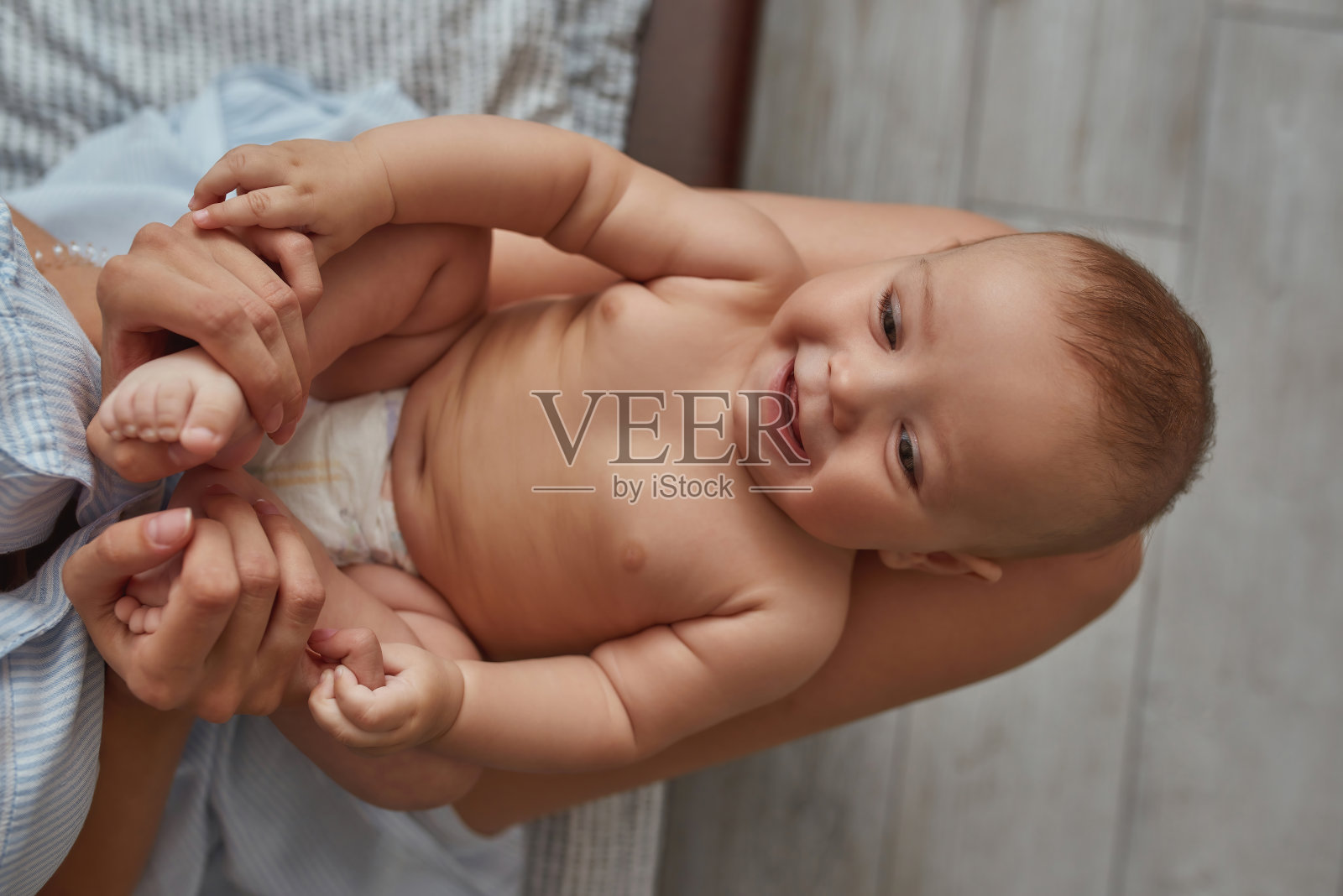 年幼的孩子喜欢赤身地坐在母亲裸露的膝盖上照片摄影图片