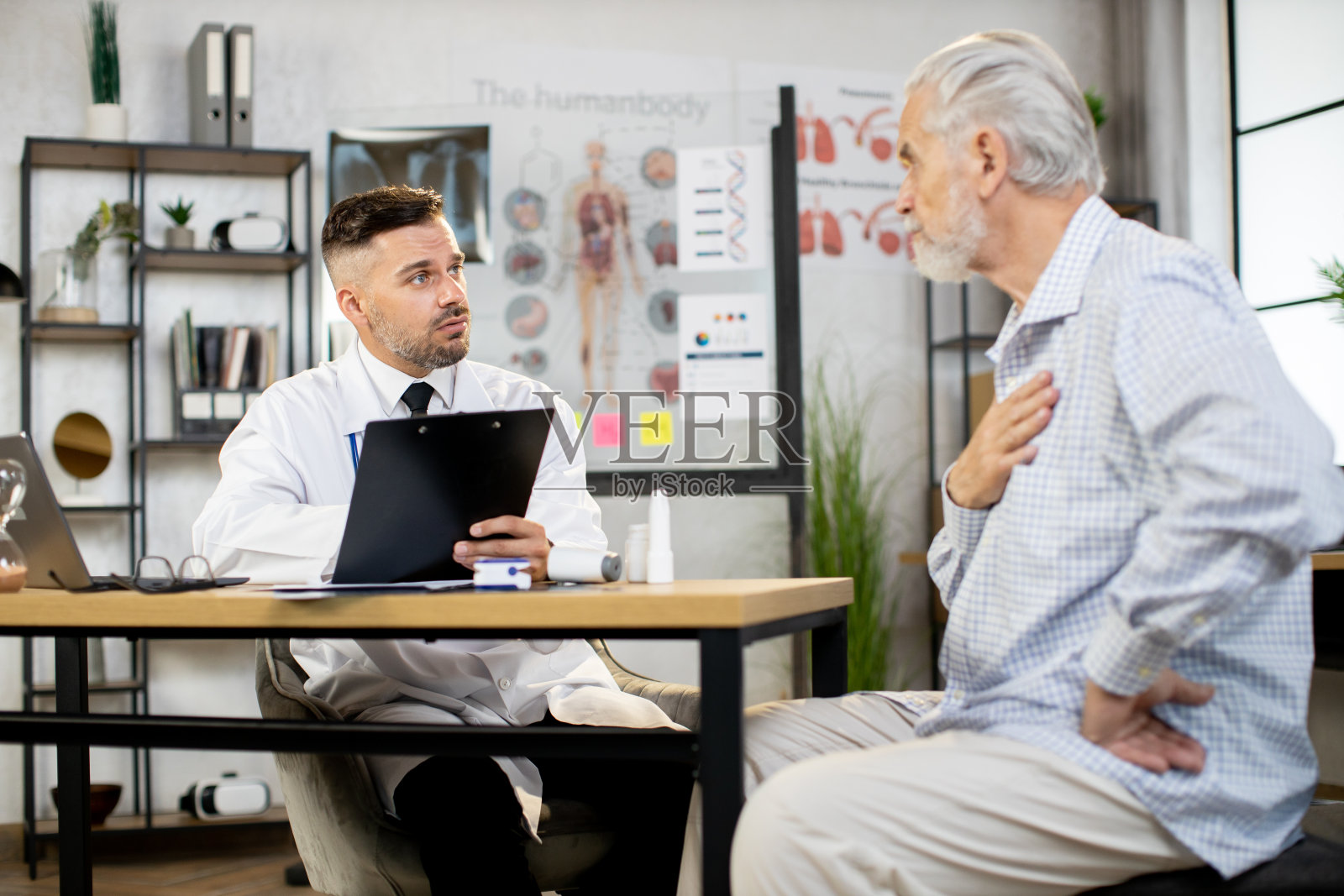 男医生拿着写字板听老病人说话照片摄影图片