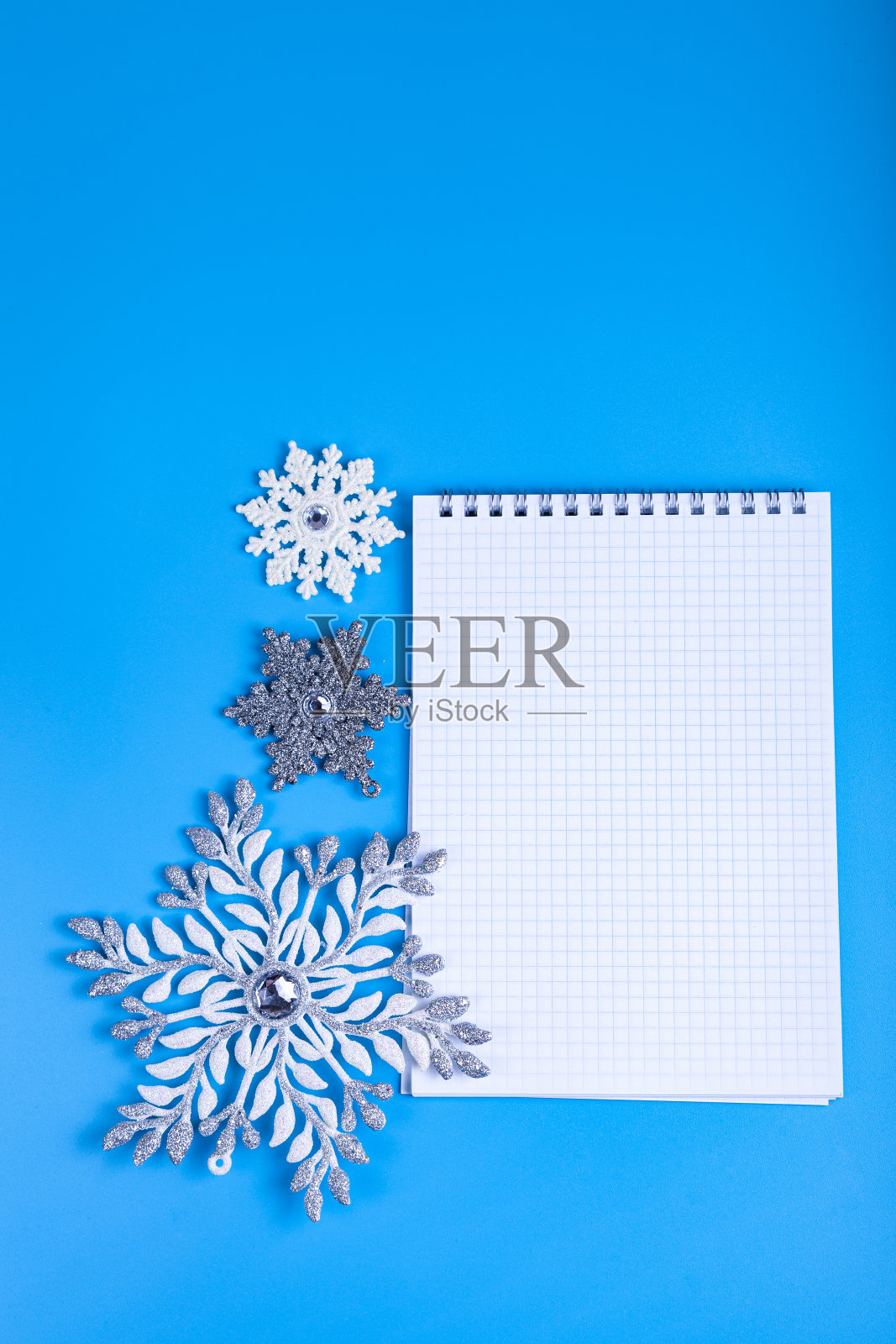 记事本和蓝色背景上的雪花。圣诞装饰。照片摄影图片