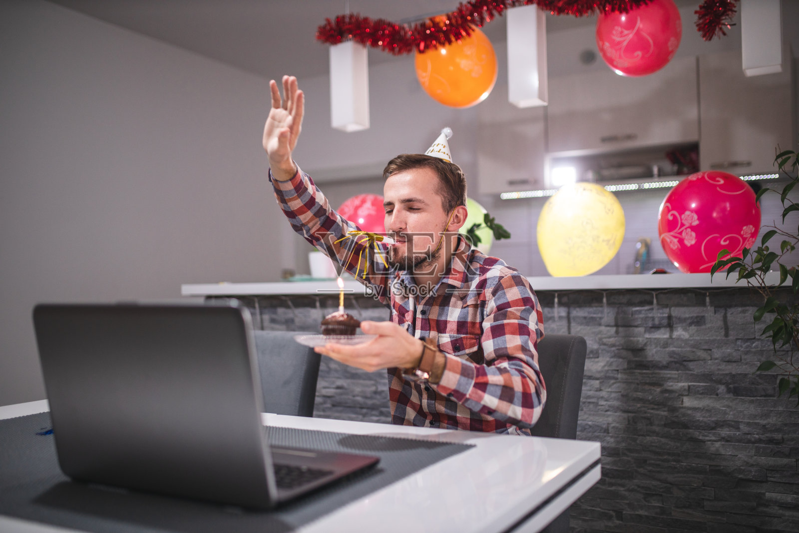 一名年轻人在大流行COVID-19冠状病毒日哨声期间与朋友视频通话庆祝生日照片摄影图片