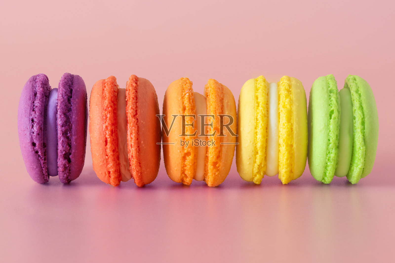 粉红色背景上的一排彩色杏仁饼干照片摄影图片