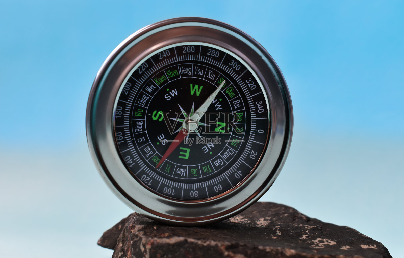 放置在岩石上的聚焦导航罗盘。照片摄影图片