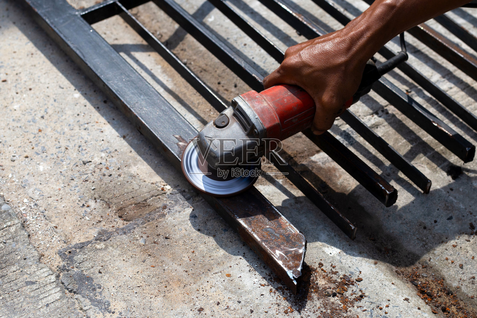 靠近点,一个人在用角磨床。铁门修复照片摄影图片