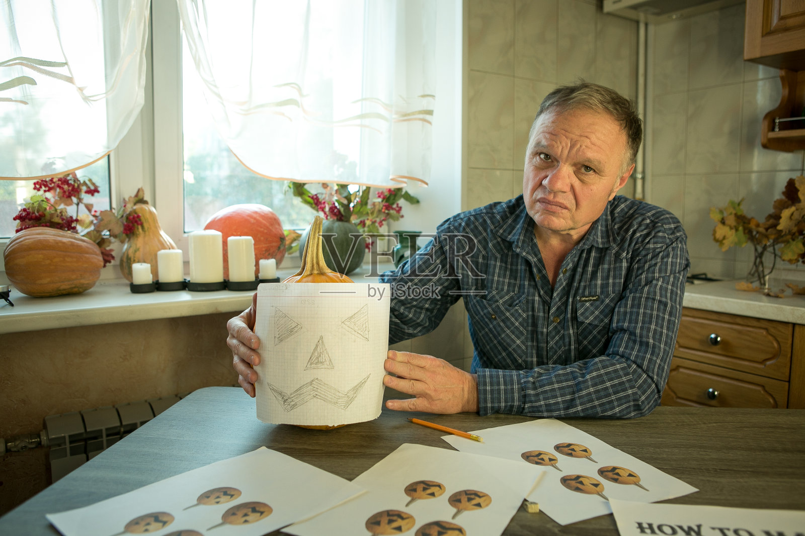 如何在家制作杰克灯?一个人在试南瓜雕刻模板。选择性聚焦和散景。照片摄影图片