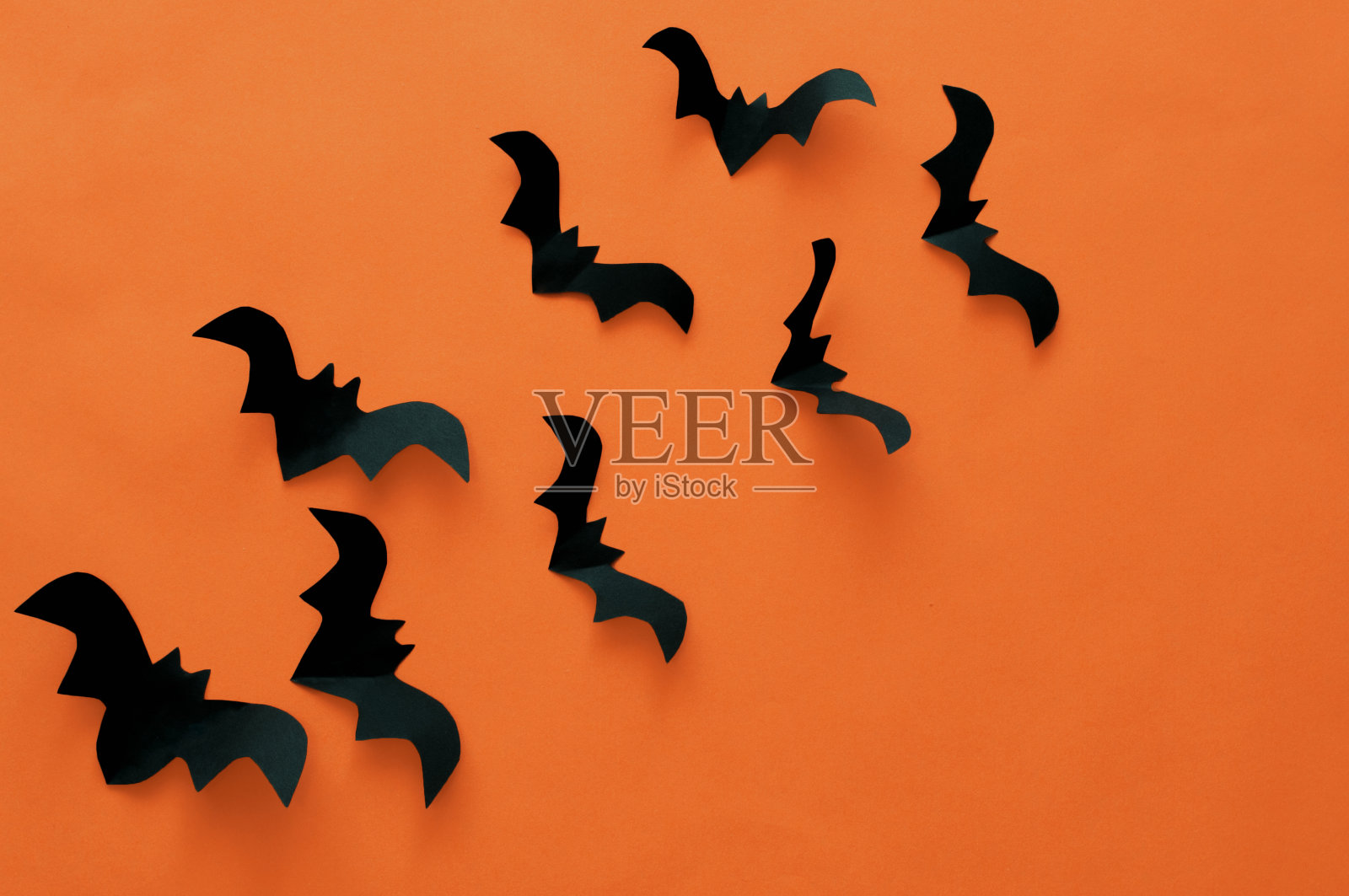 万圣节概念,橘色背景上的黑纸蝙蝠照片摄影图片