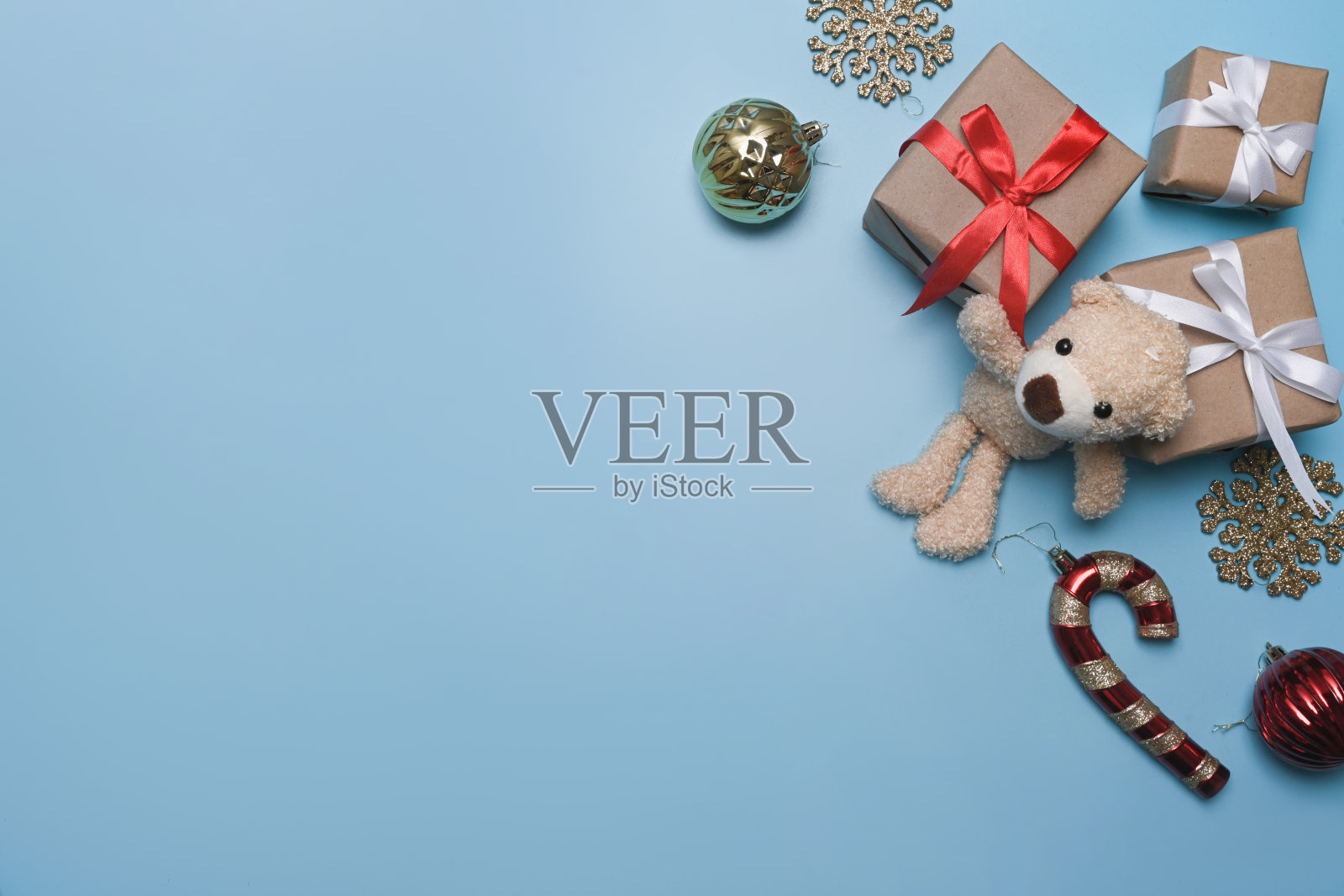 蓝色背景上的圣诞装饰品、泰迪熊和礼品盒。照片摄影图片