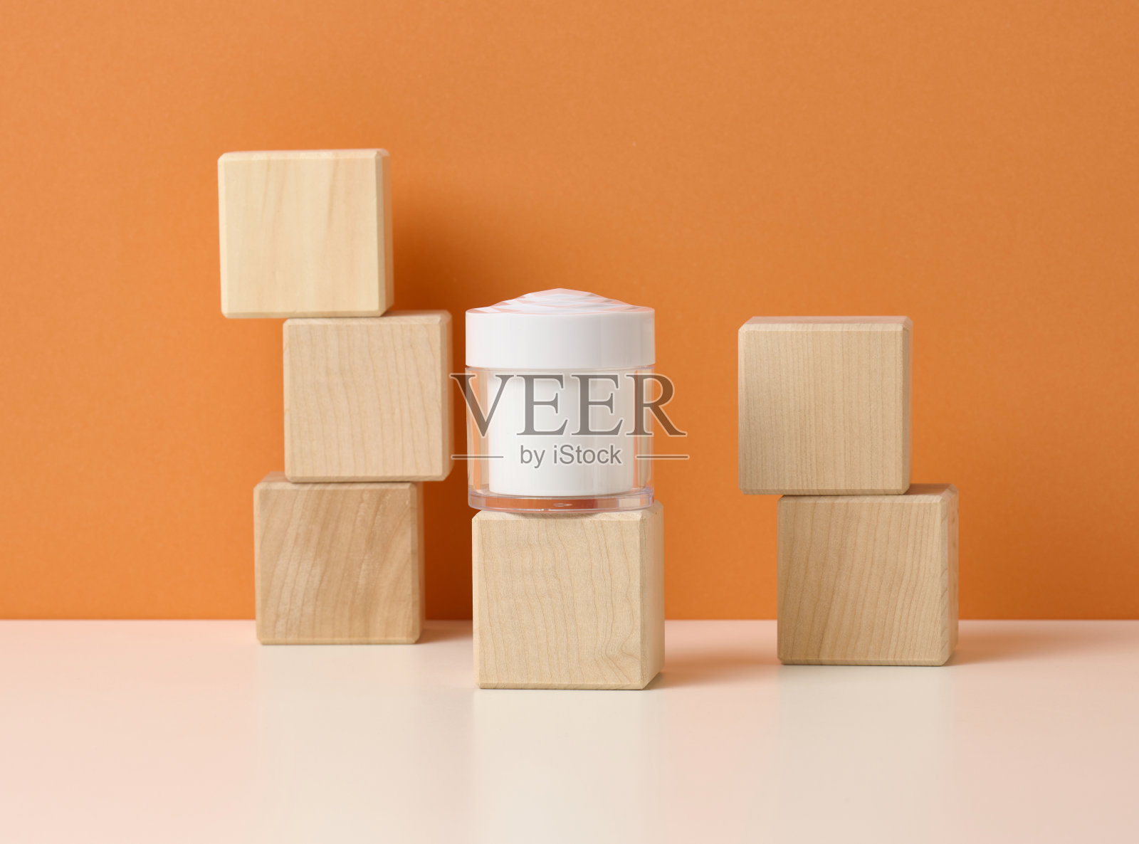 白色桌子上的白色化妆品空罐,橙色背景。乳霜、凝胶、血清的包装,广告及产品推广。模拟了照片摄影图片