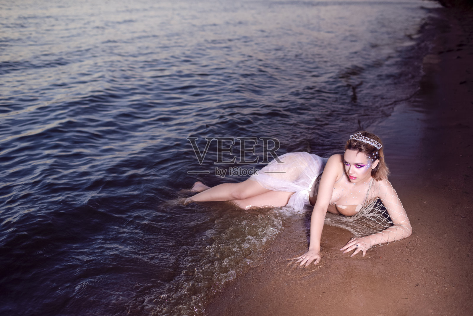 充满激情的性感美丽的黑发女性在黑色裙子在树上,戴着贝壳装饰的皇冠和长黑珍珠项链。垂直组成照片摄影图片