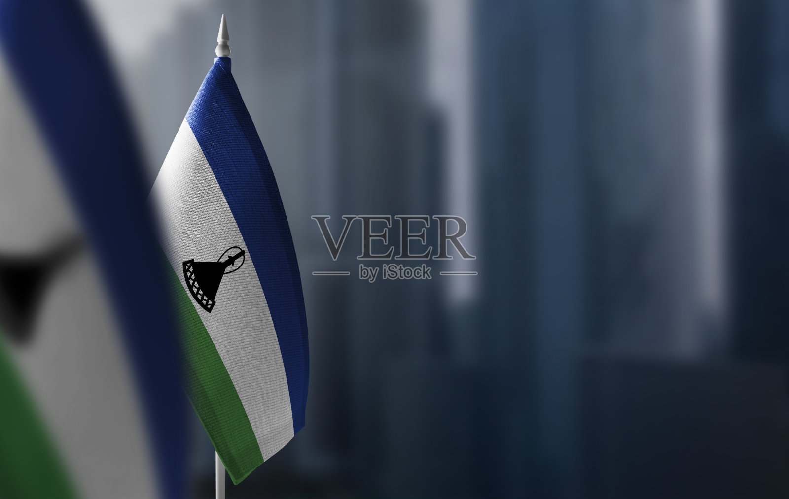 城市模糊的背景上悬挂着莱索托的小国旗照片摄影图片