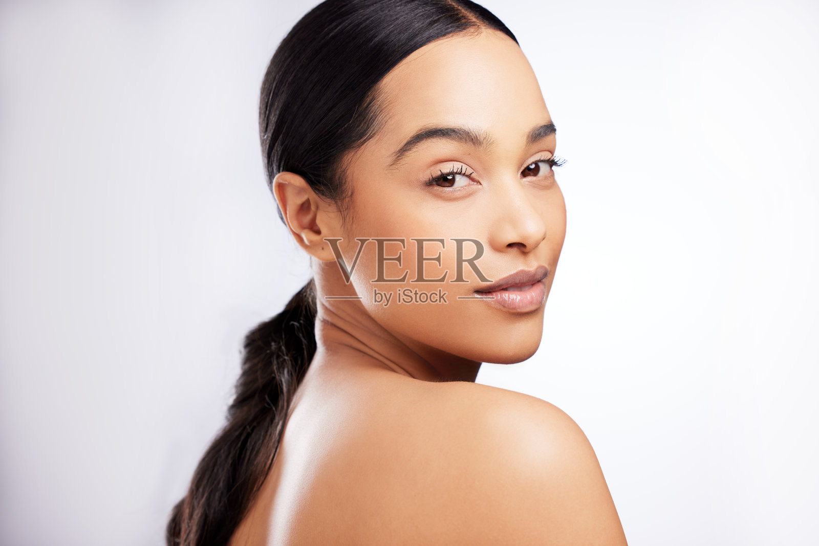 一个美丽的年轻女子在白色背景下摆姿势的画室肖像照片摄影图片