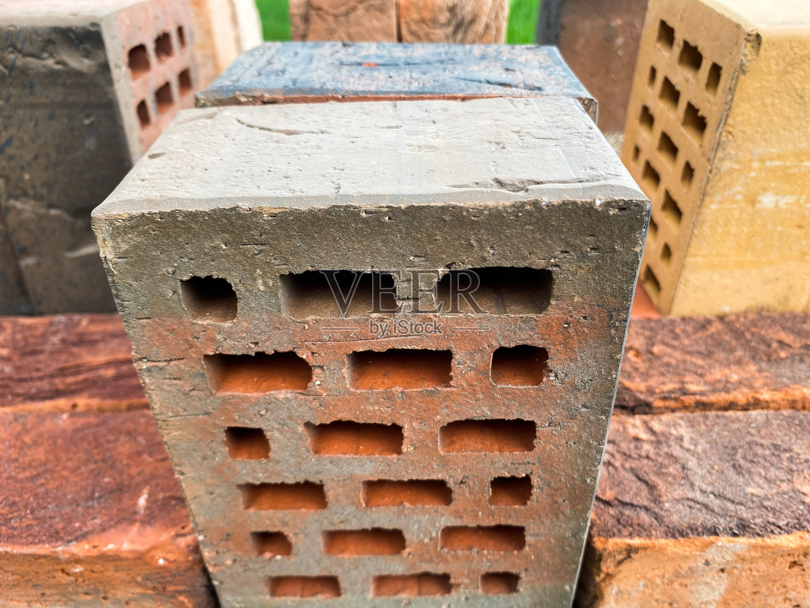 不同类型的砖块漂亮地堆放在绿色的草地上照片摄影图片