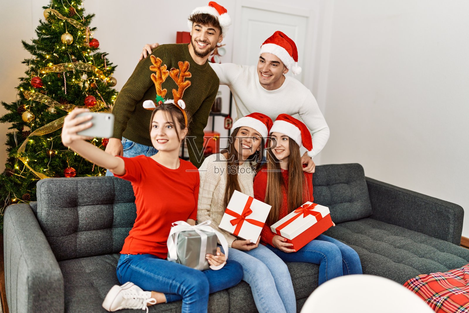 一群年轻人拿着圣诞礼物在家用智能手机自拍照片摄影图片